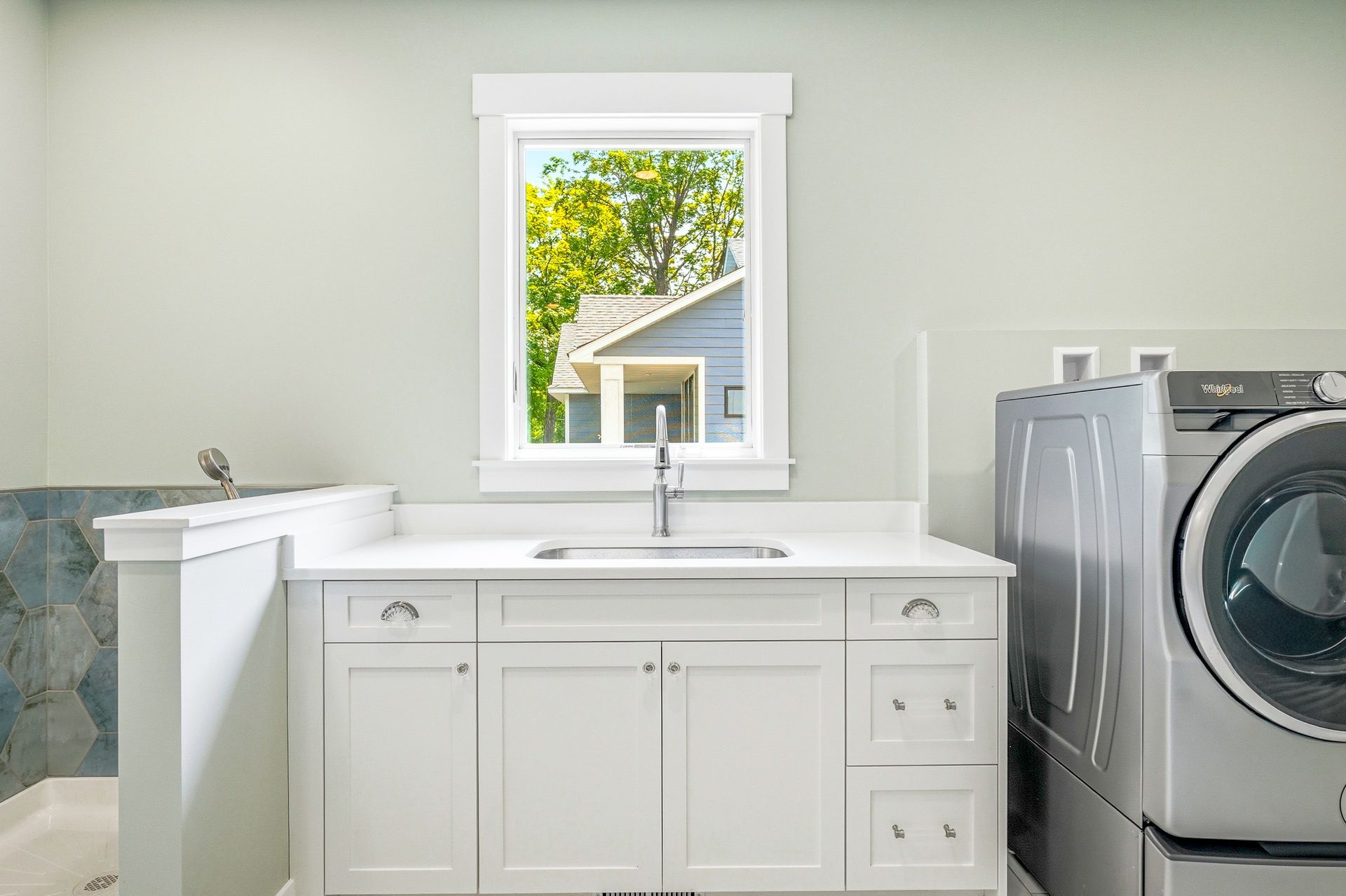 White shaker laundry room cabinets in Chisago City, MN with countertop workspace, sink, and built-in storage.