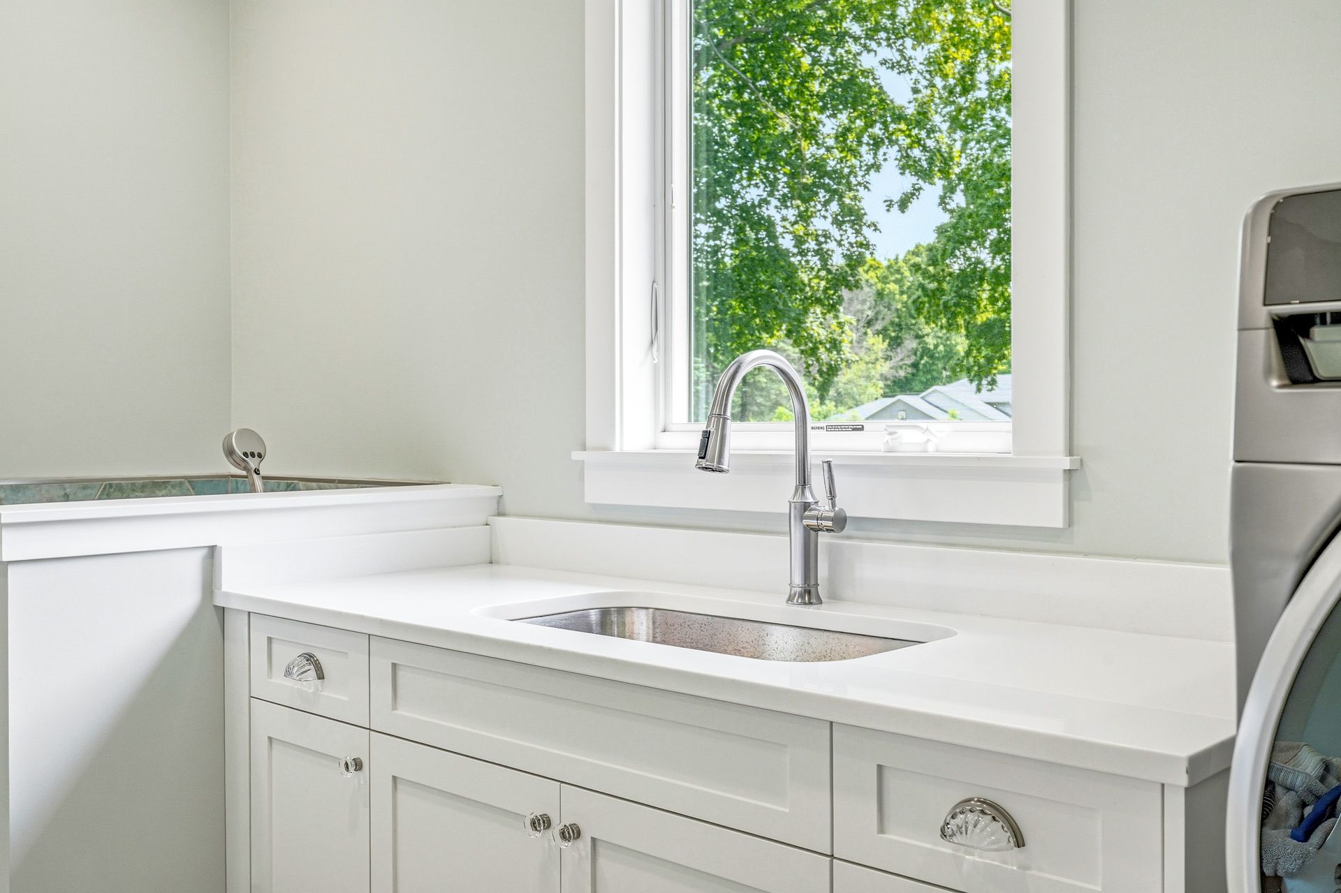 White shaker laundry room cabinetry in Chisago City, MN with a utility sink and countertop workspace.