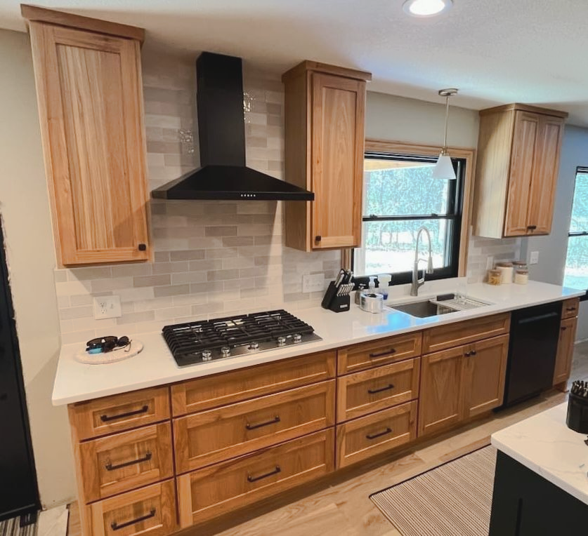 Natural wood kitchen cabinetry with drawer storage and white countertops by Twin River Cabinets