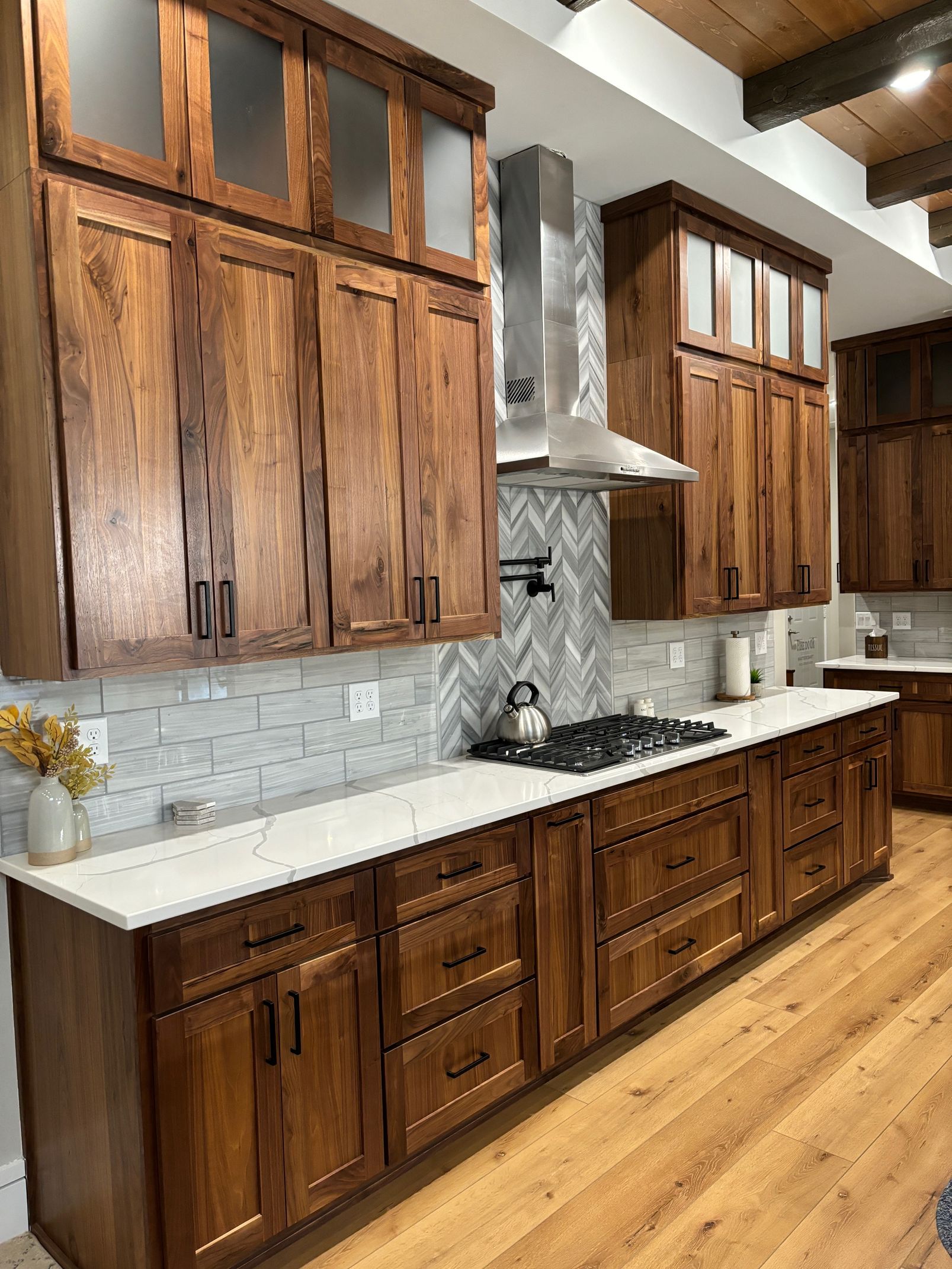 Walnut Luxe Collection kitchen cabinetry with rich natural wood grain, tall cabinets, and modern black hardware.
