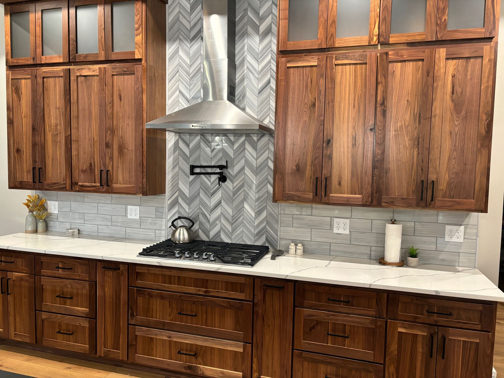 Walnut Luxe Collection kitchen cabinetry surrounding a statement range hood with custom drawer storage.