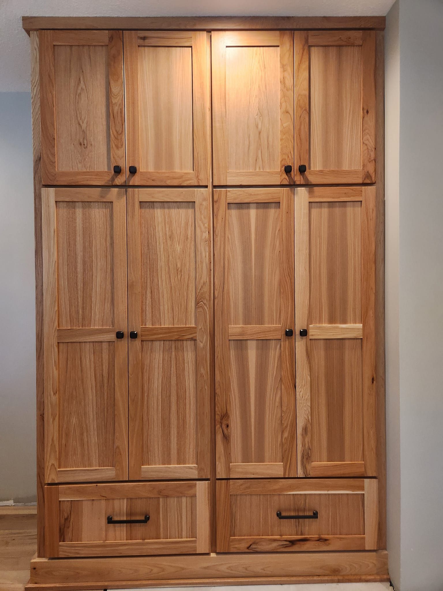 Floor-to-ceiling natural wood pantry cabinets with inset panel doors
