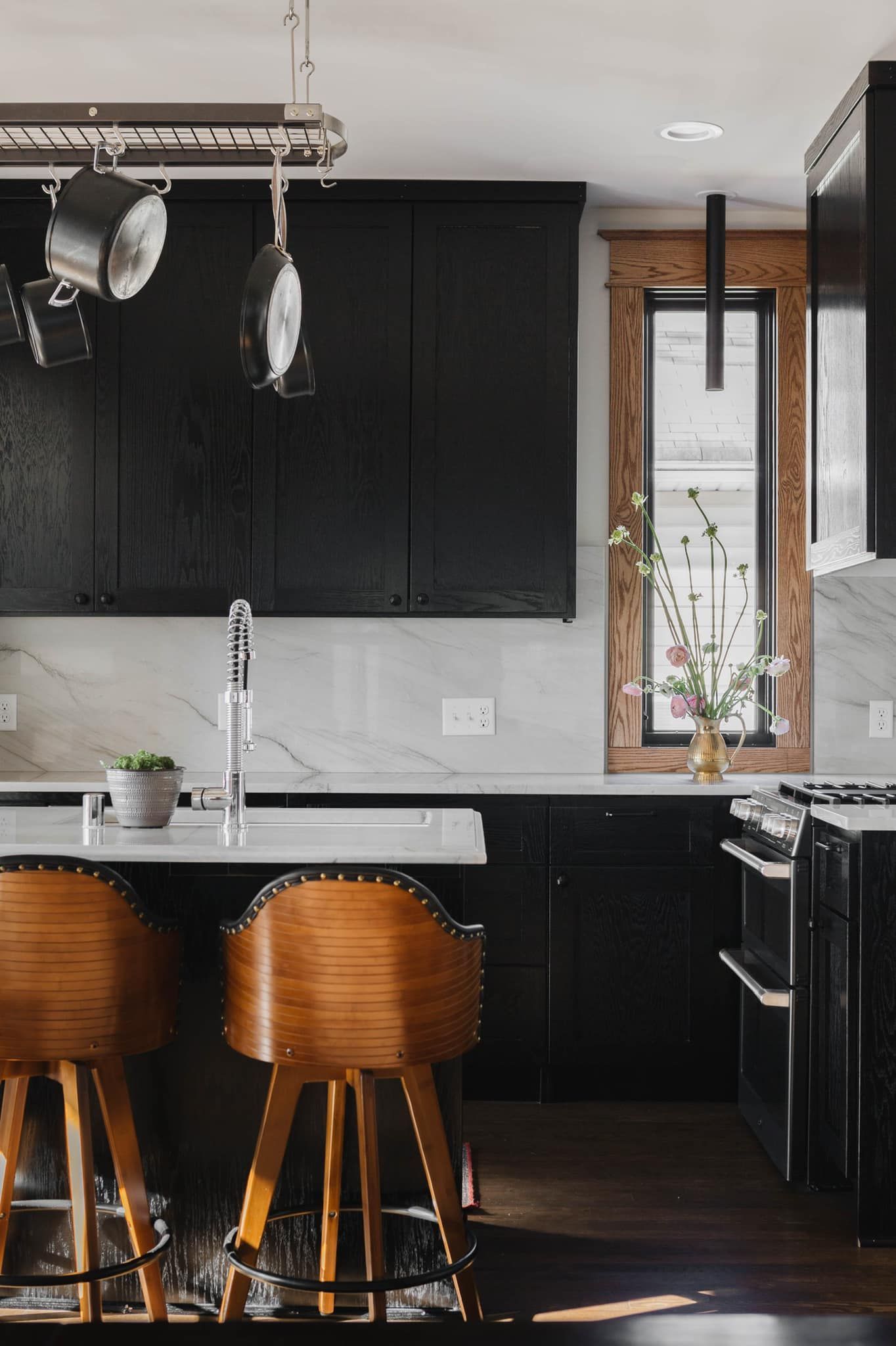 Black oak Signature Collection kitchen cabinets with natural wood window trim and white countertops in Inver Grove Heights, Minnesota.