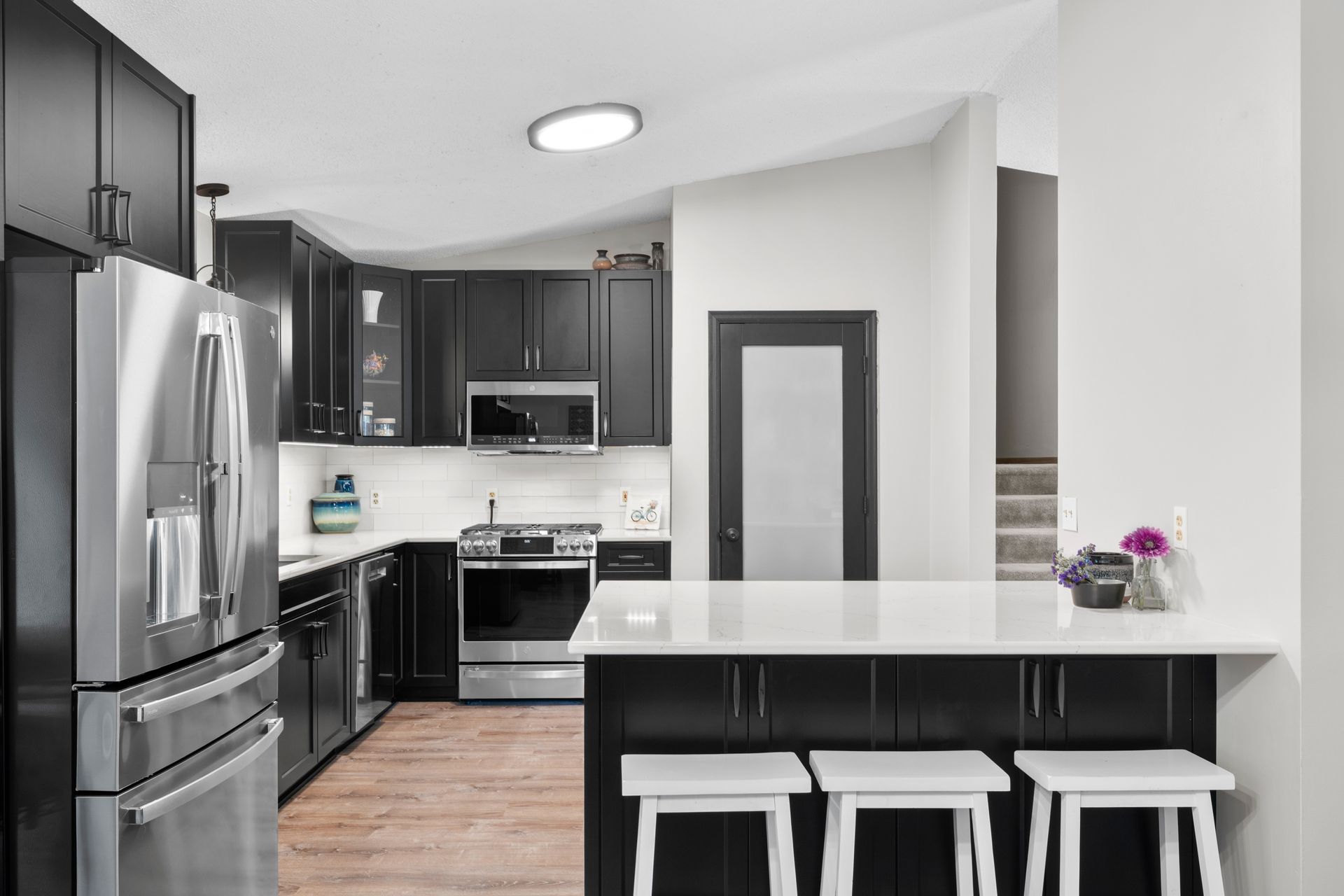 Black Casa Collection kitchen cabinetry with large island and white countertops in Lino Lakes, Minnesota.