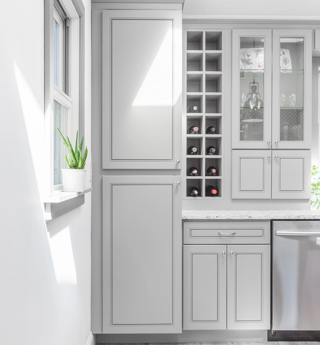 Greige Summit by TRC semi-custom cabinetry with built-in wine storage, glass-front cabinets, and countertop storage.