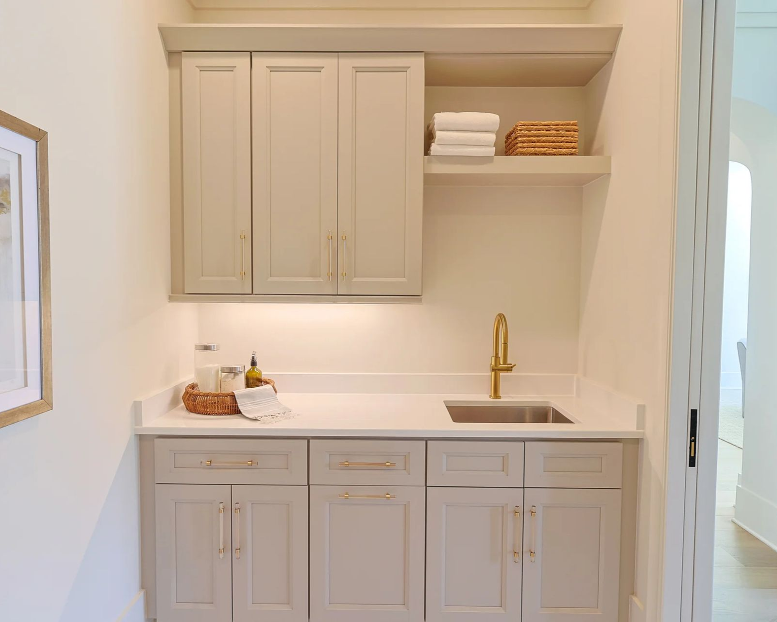 Semi-custom cabinetry in Pebble, laundry room with gold hardware and open shelving.