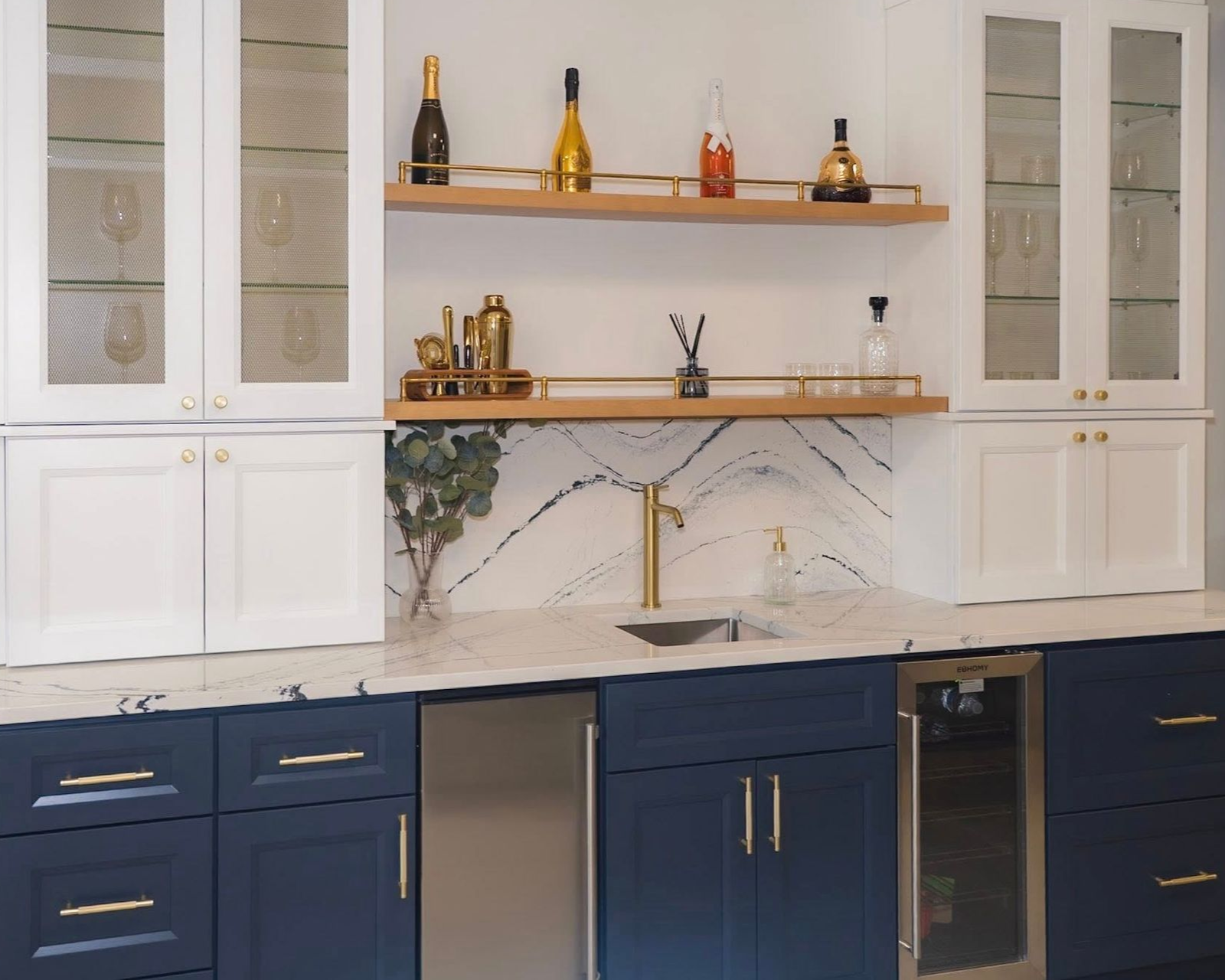 Two-tone Summit bar cabinetry in Naval and white with glass doors, open shelving and gold hardware.