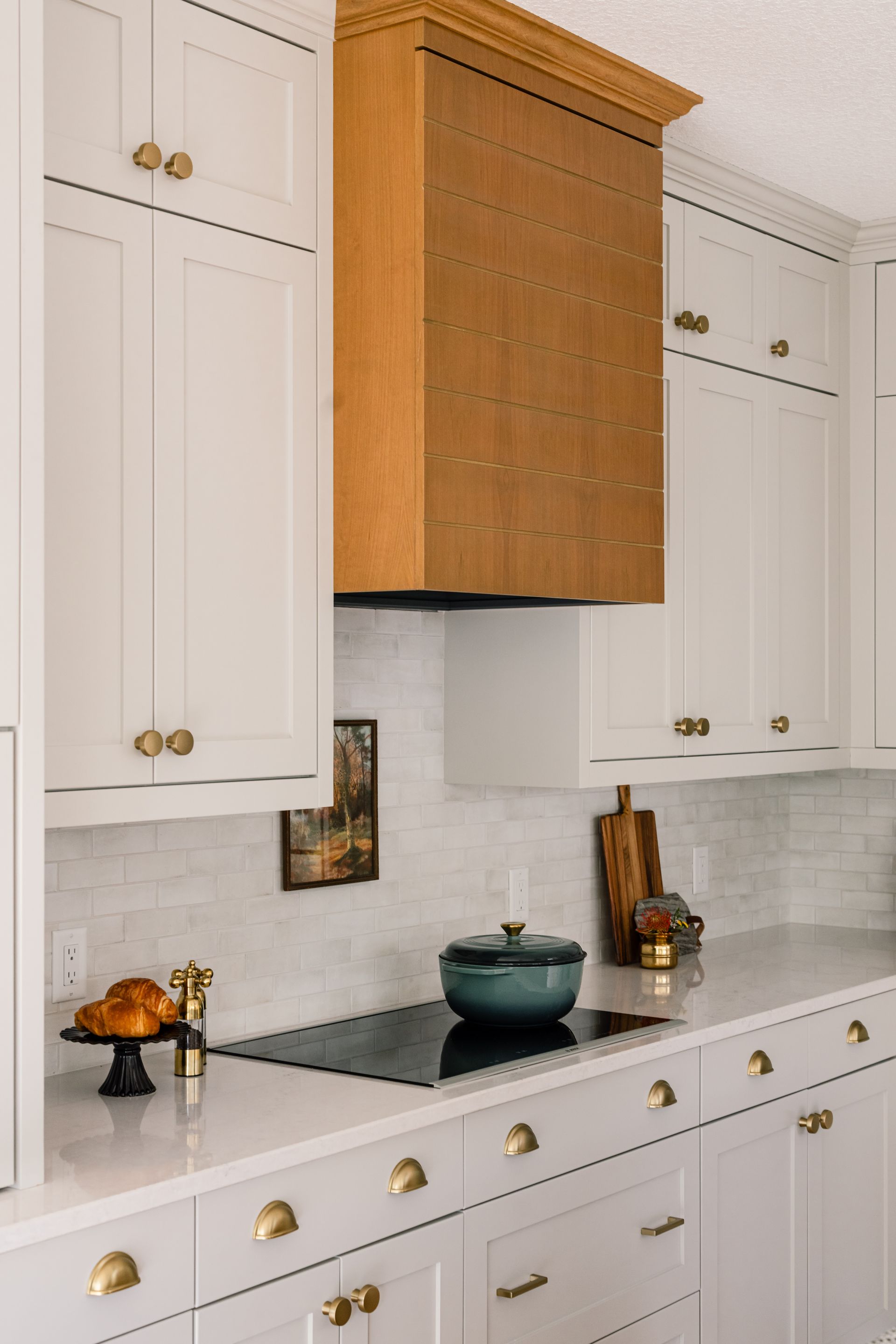 Custom natural wood range hood surrounded by white kitchen cabinetry in Woodbury, Minnesota.