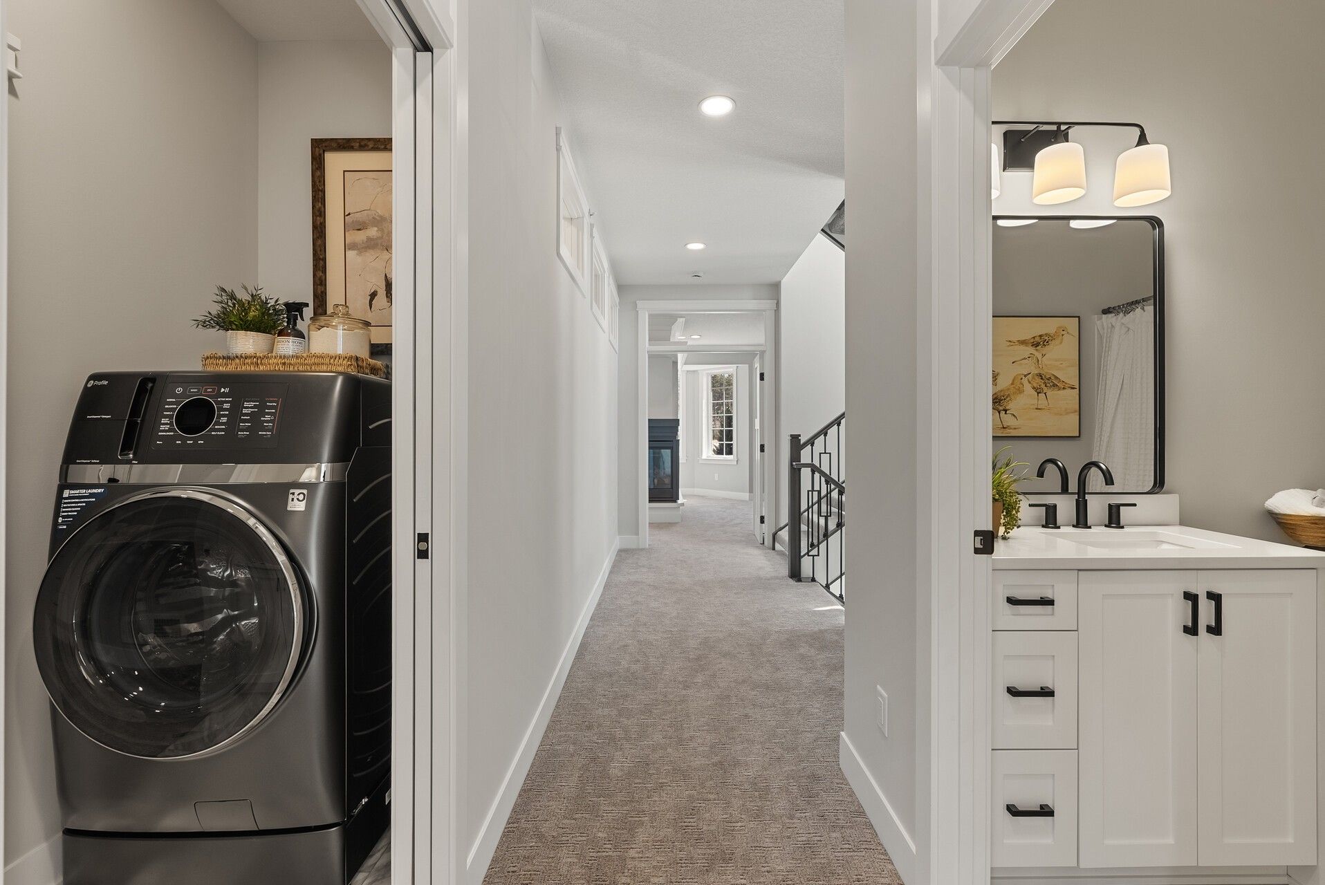 White shaker bathroom vanity with black hardware beside a laundry area in a Woodbury, MN home.
