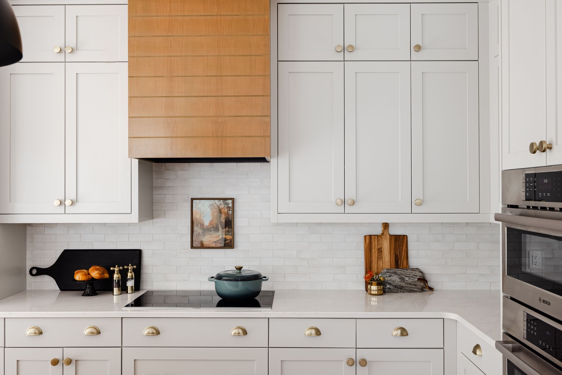 White custom kitchen cabinets with brass hardware and natural wood range hood in Woodbury, Minnesota.