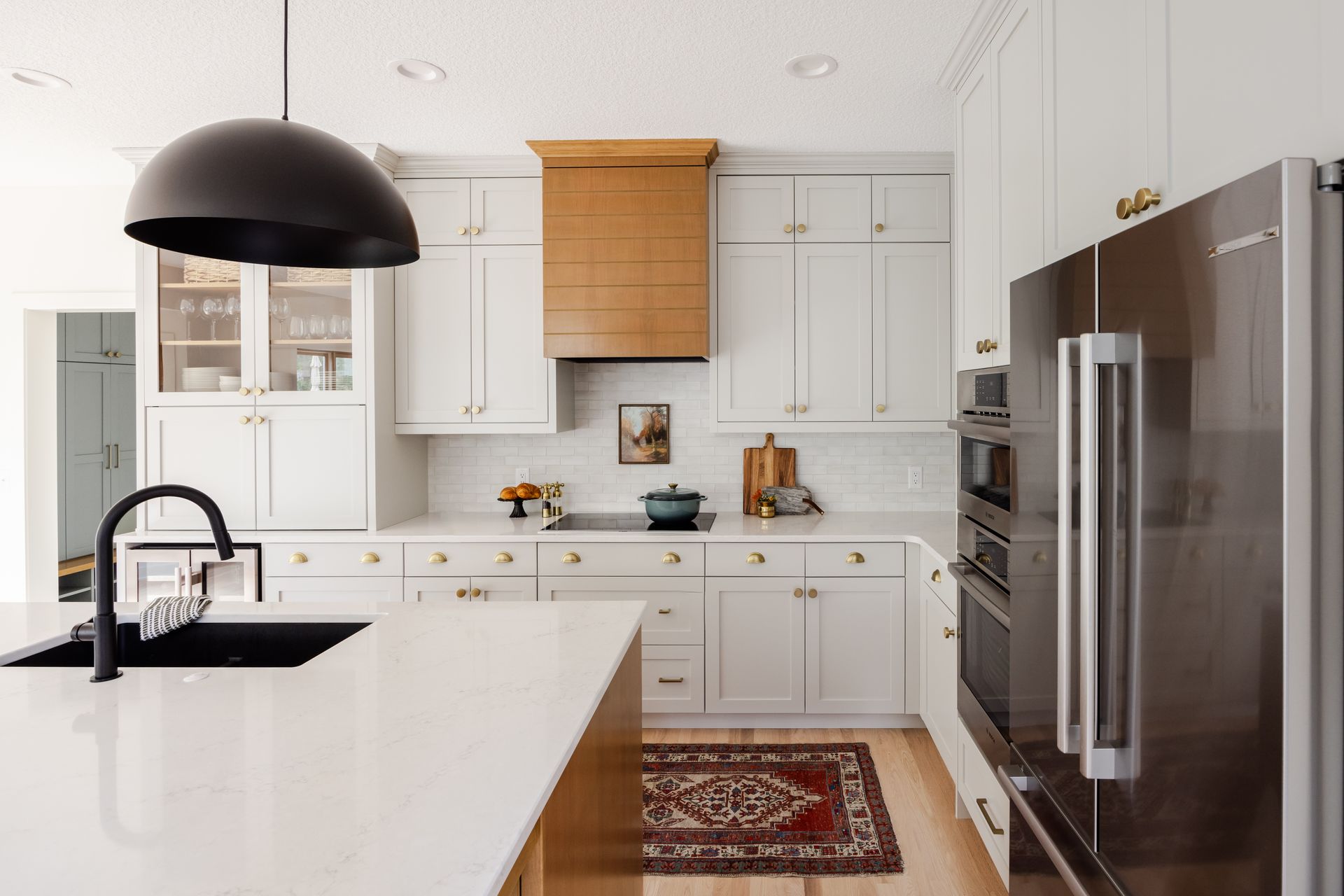 White custom kitchen cabinets with natural wood range hood and brass hardware in Woodbury, Minnesota.