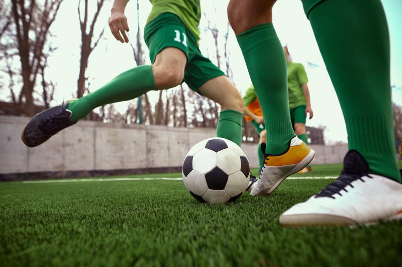 A group of soccer players are playing soccer on a field.