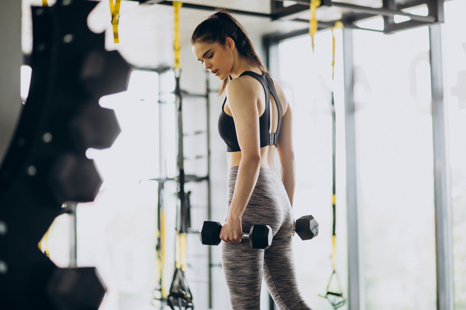 A woman is lifting a dumbbell in a gym.
