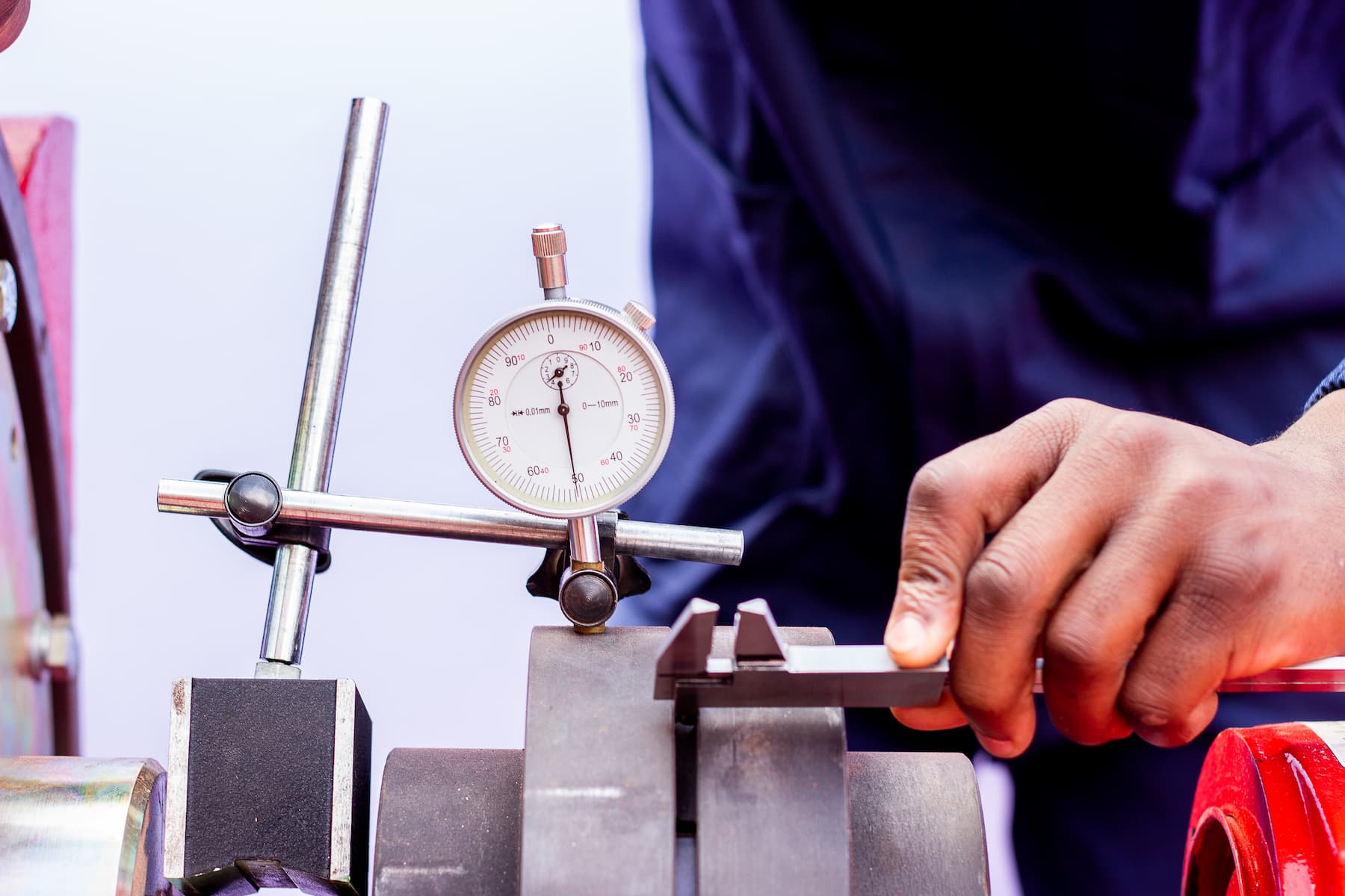 Worker using a dial indicator to measure a metal part in a machine shop