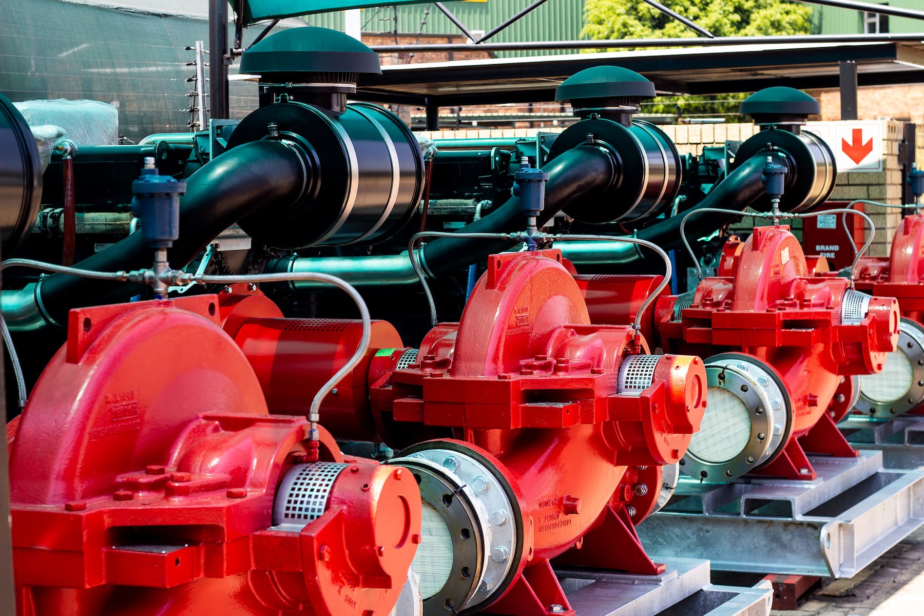 Row of red industrial pumps and black pipes in a mechanical facility