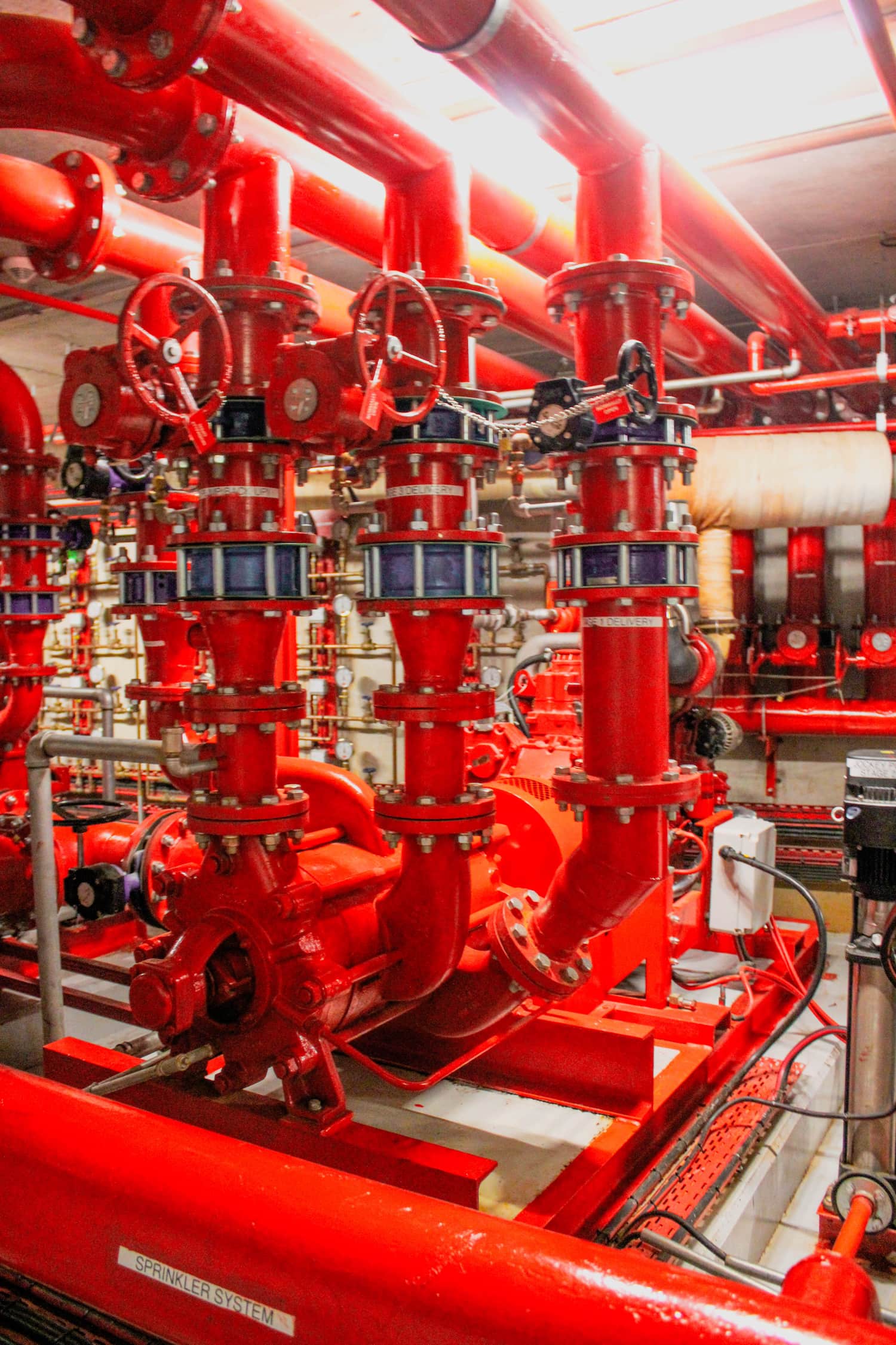 Red industrial fire sprinkler pipes and valves in a mechanical room
