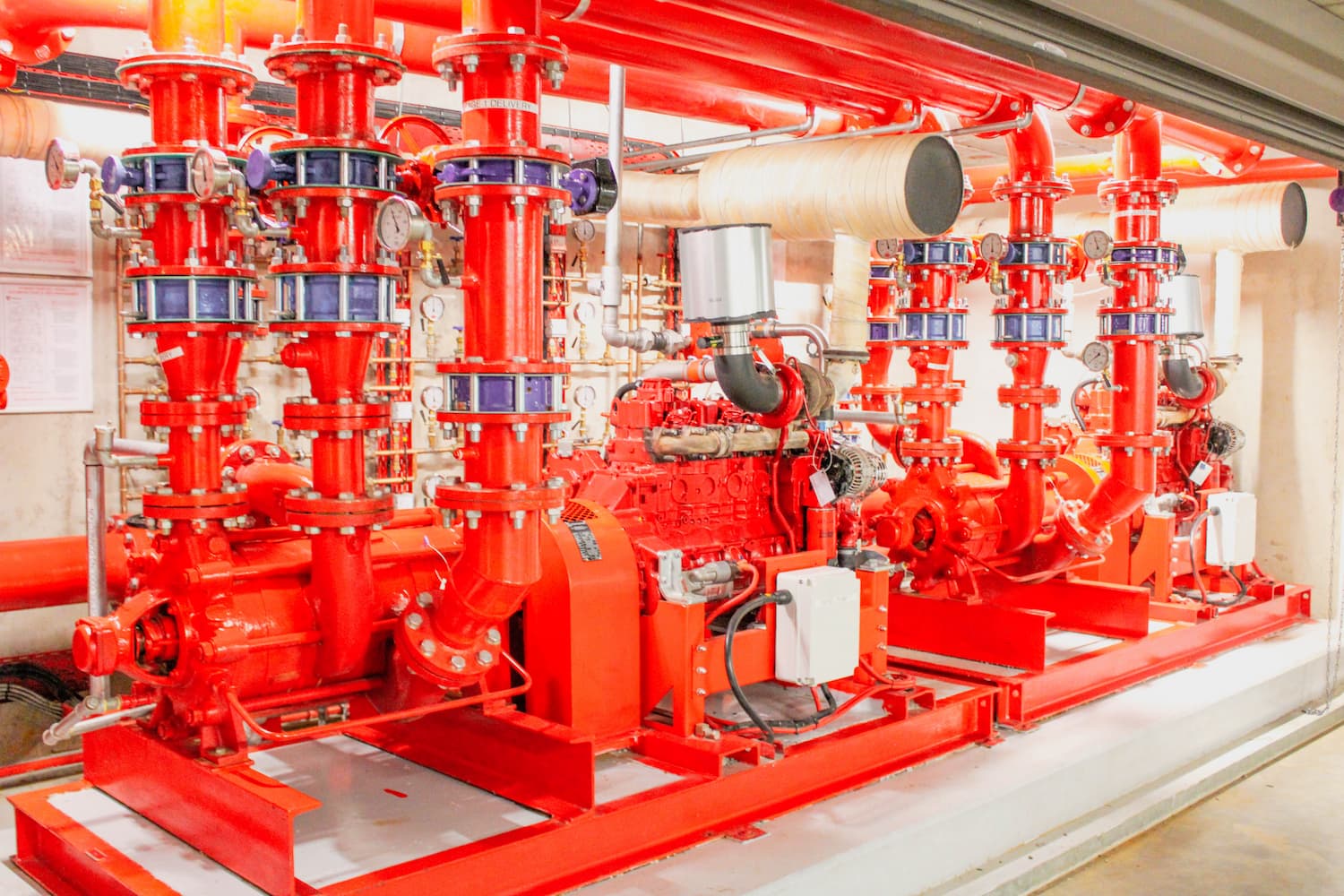 Red fire sprinkler piping system in a mechanical room with valves and pumps