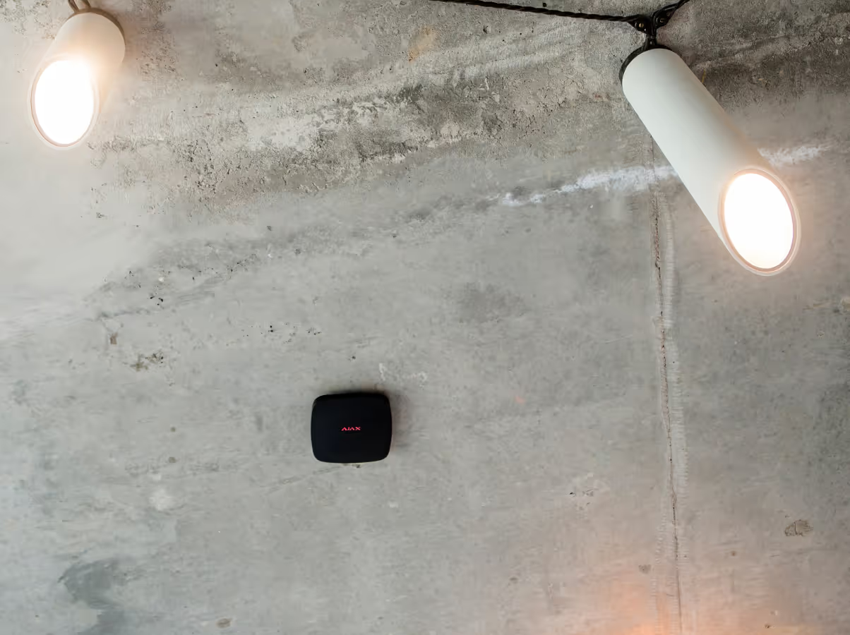 A concrete ceiling featuring two white cylindrical spotlight fixtures and a small black square motion sensor  — Cussler NQ in Proserpine, QLD