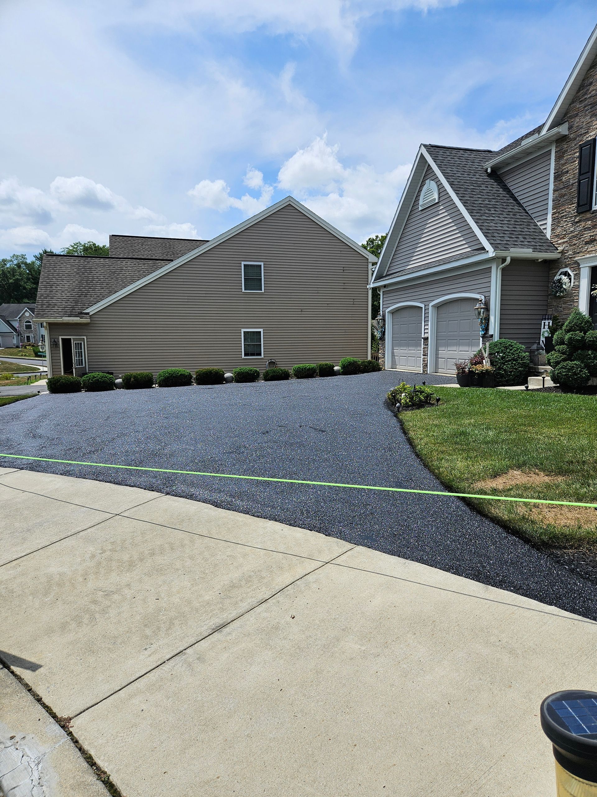 A suburban home featuring a beige, surreal-looking wall with wave-like indentations beside a two-car garage and driveway.