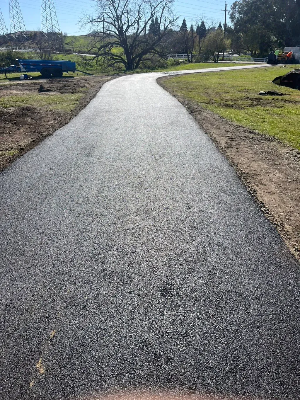 Curved paved path through a grassy park under bright sunlight
