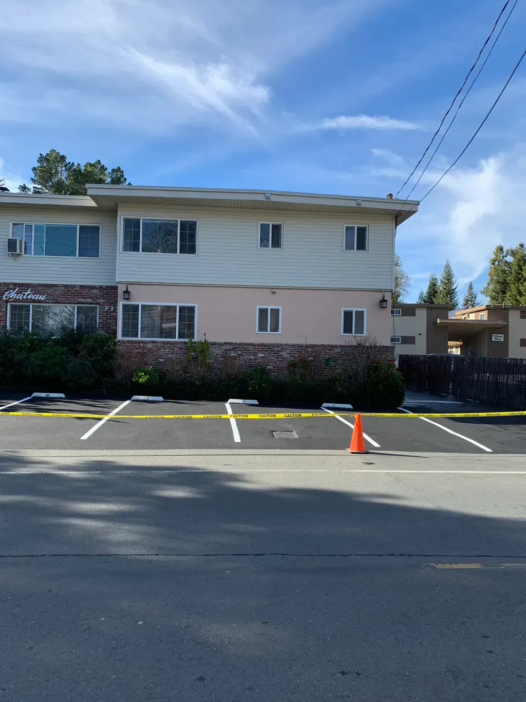 Apartment building with parking lot and orange cone under a clear blue sky