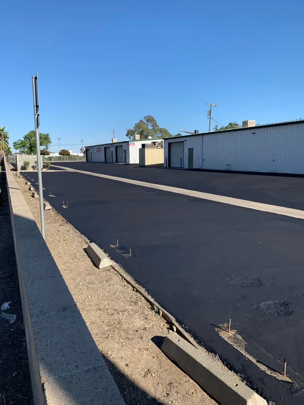 Empty paved lot with white storage buildings and a blue sky