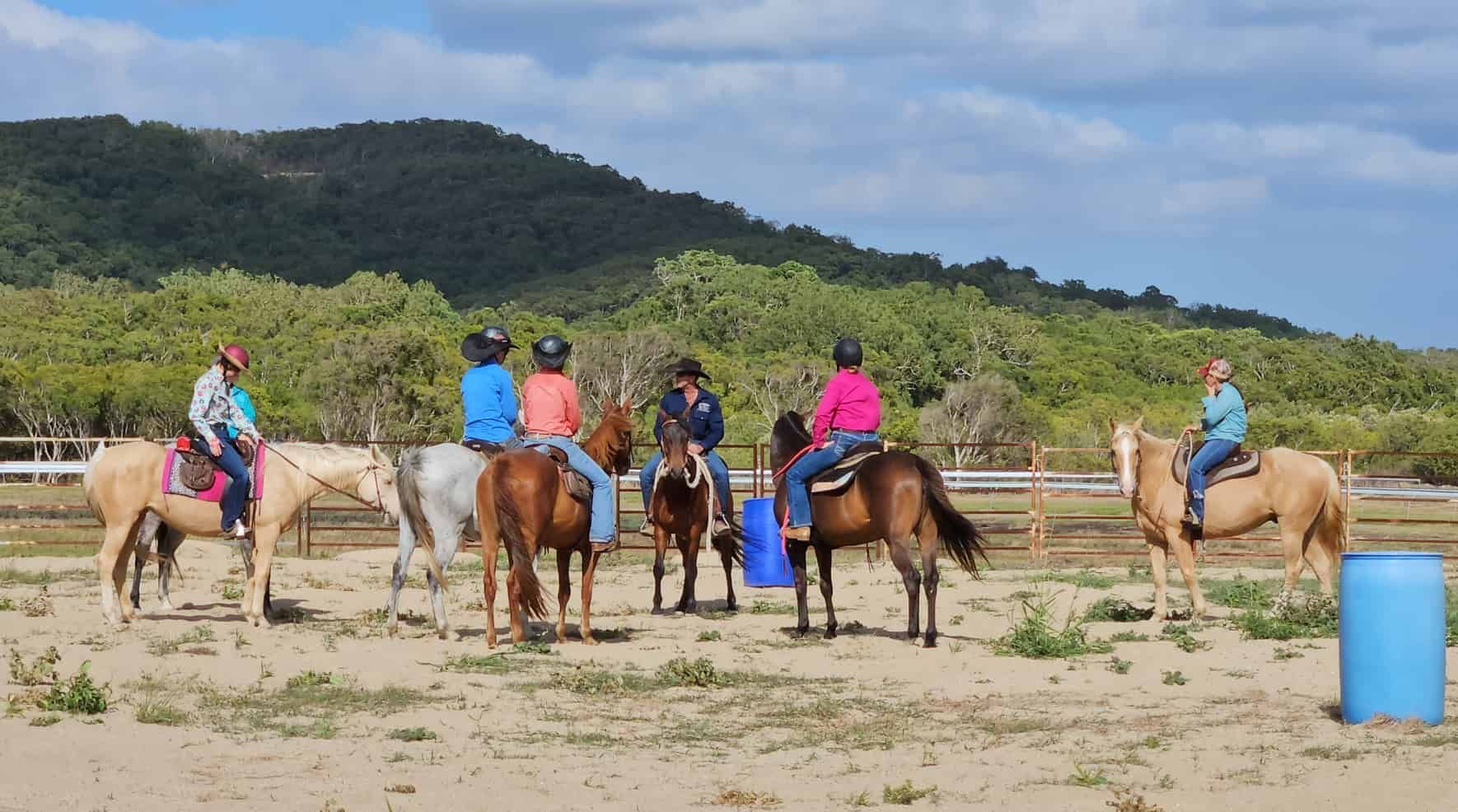A Group Of People Are Riding Horses In A Field — Jono Battle Equine Services In Walkamin, QLD