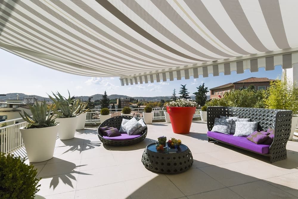 A Patio With A Striped Awning And Couches — Southern Blinds & Awnings In Bundanoon NSW