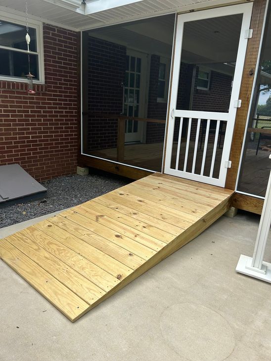 A wooden ramp is leading to a screened in porch.