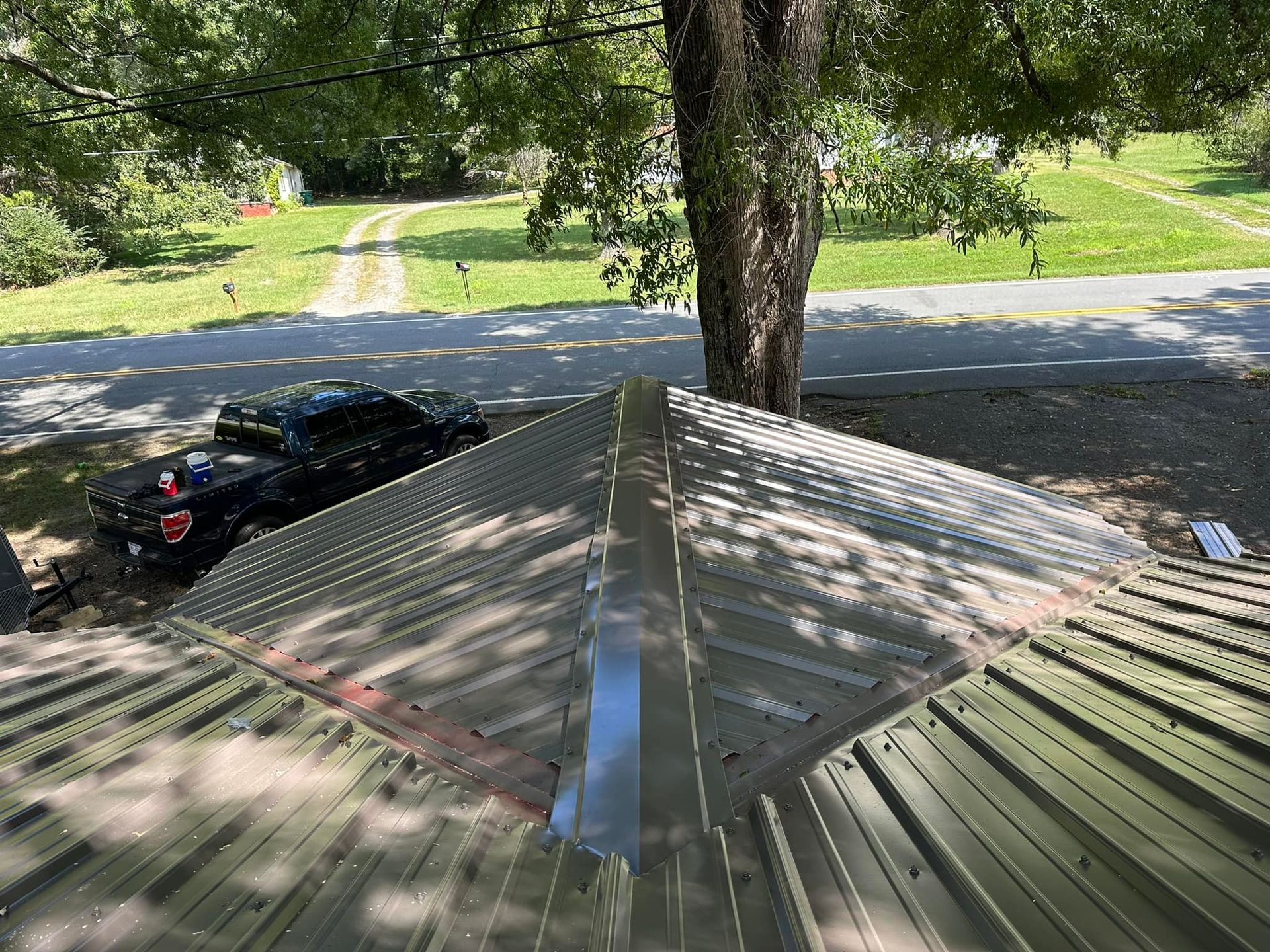 A car is parked on the roof of a house next to a tree.