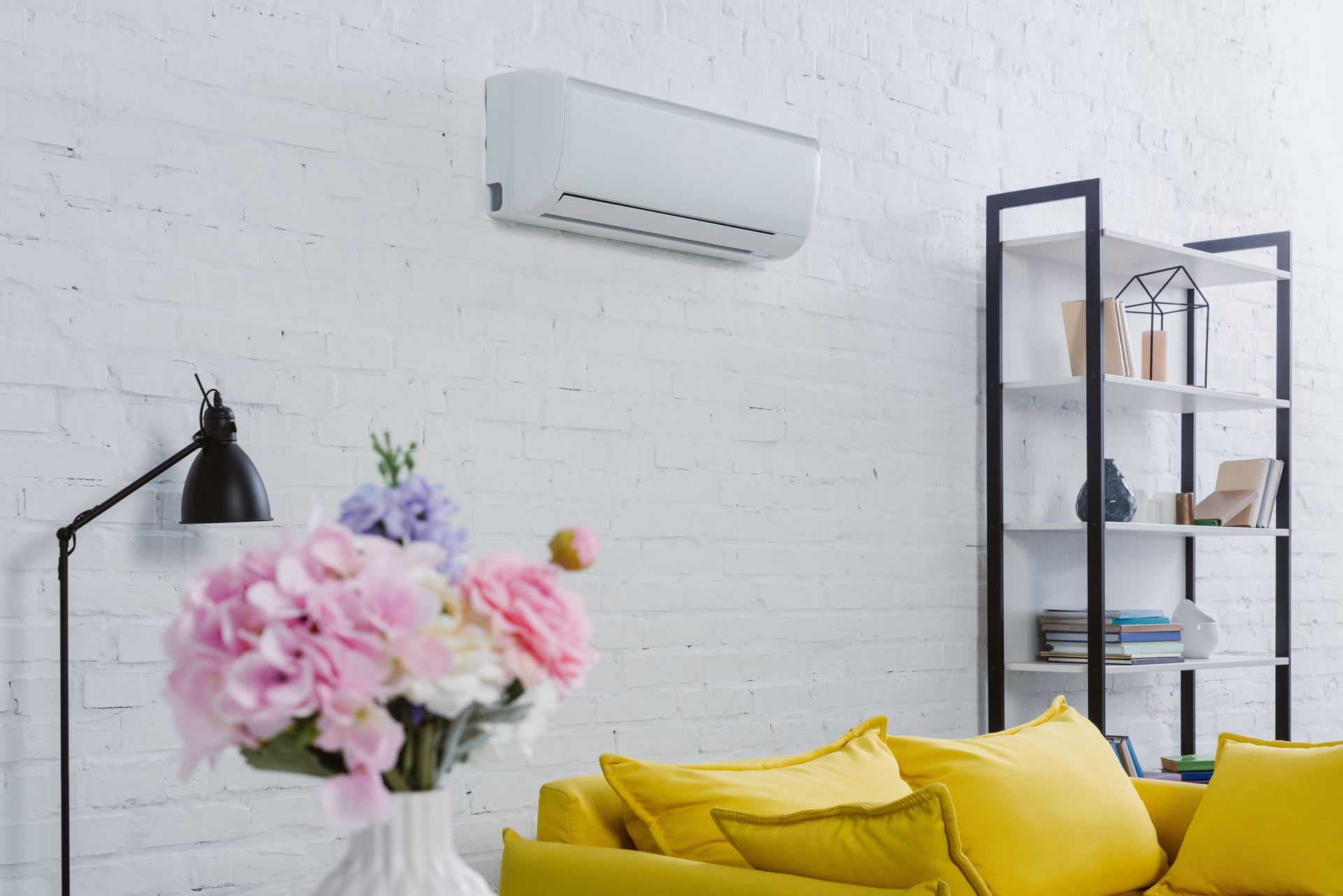 A person repairs a white wall-mounted furnace with a wrench, near yellow gas pipes.