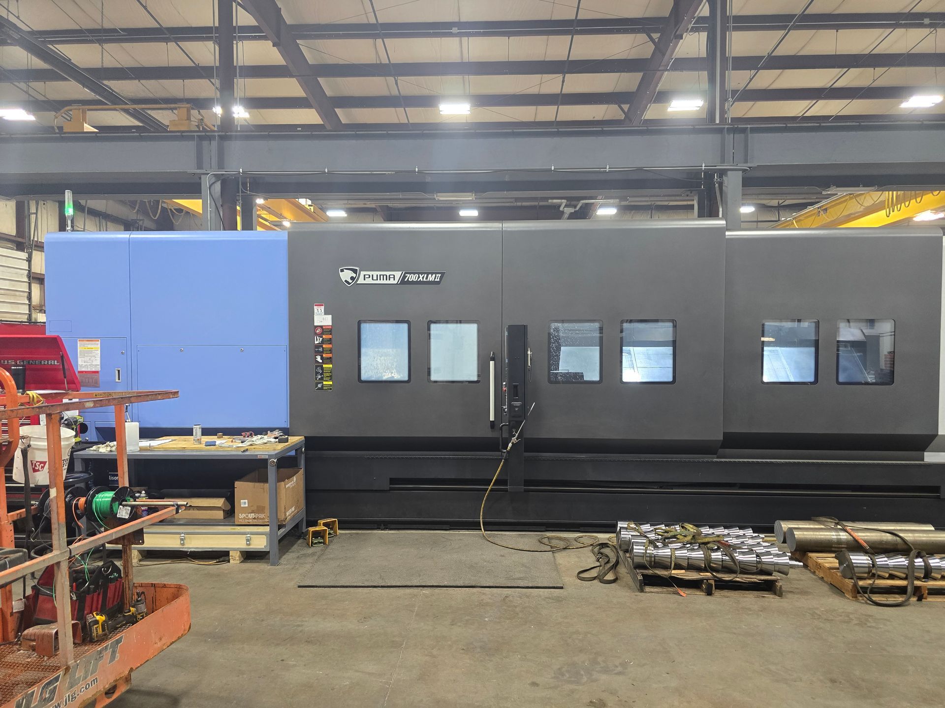 Large industrial machine in a warehouse, with blue and dark gray panels and small windows.