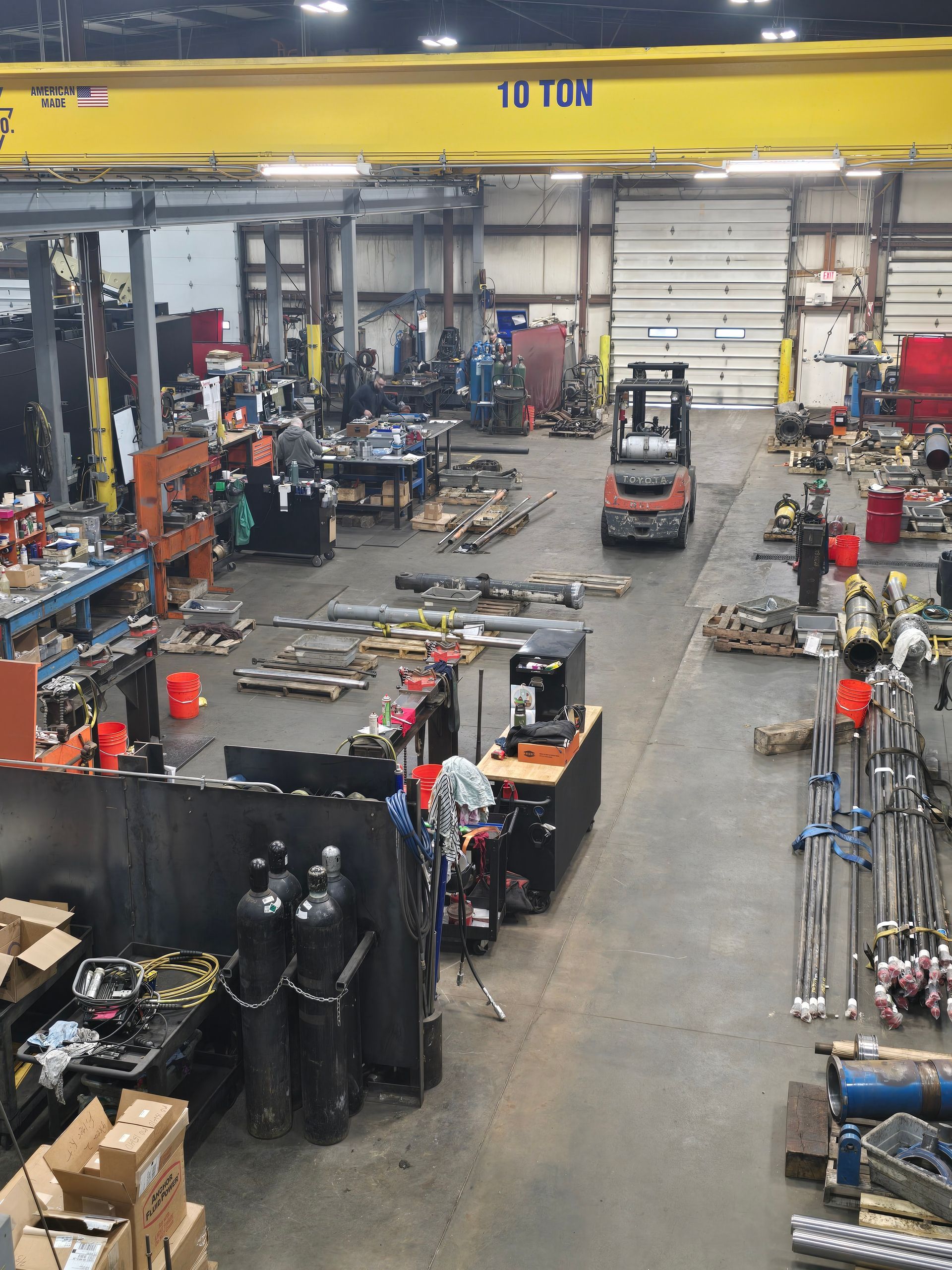 Large auto repair shop with cars, tools, equipment, and workbenches inside a warehouse-like garage.