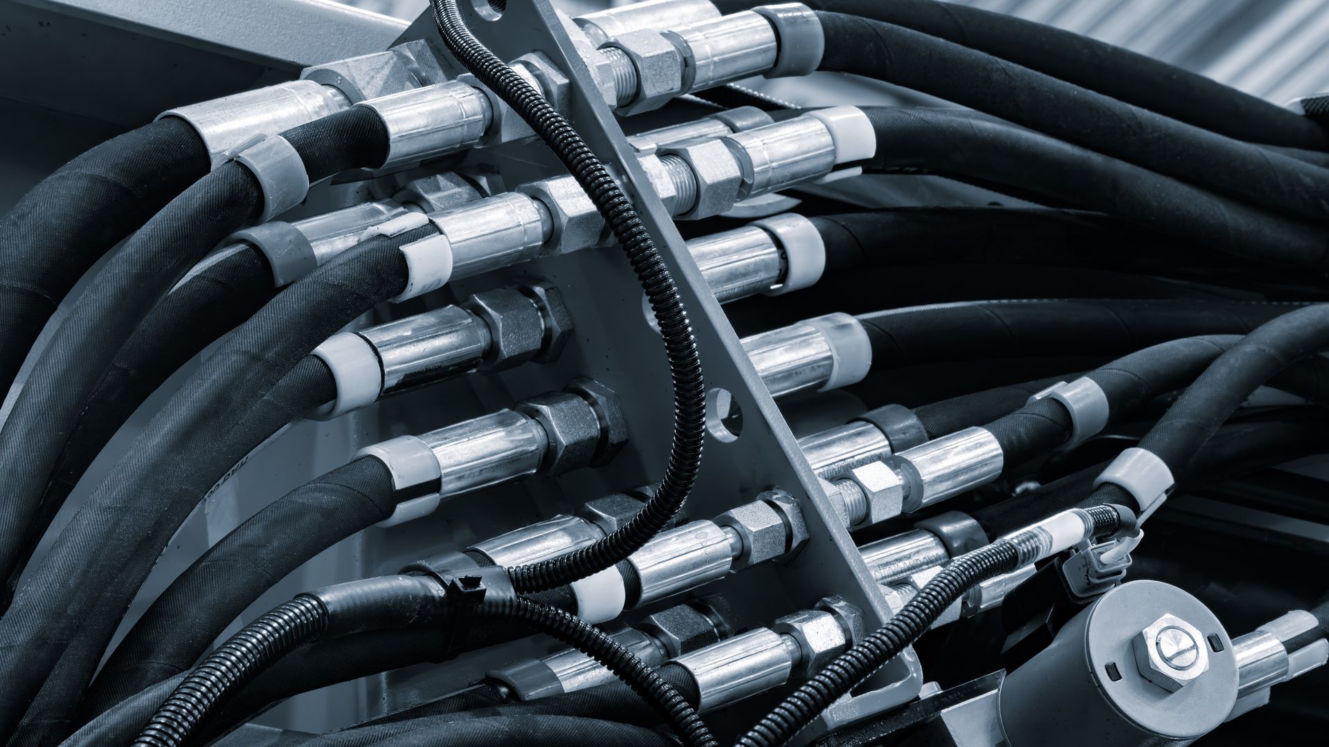 Close-up of hydraulic hoses and metal fittings in industrial machinery. Close-up of hydraulic hoses and metal fittings in industrial machinery.