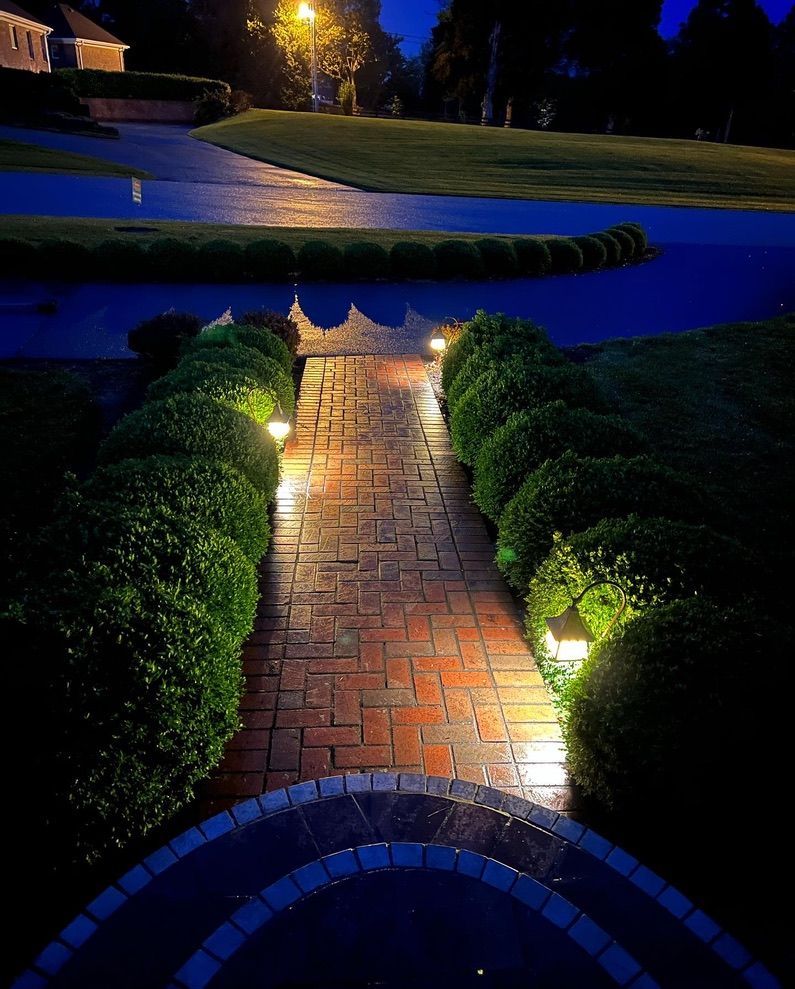 A brick walkway is lit up at night