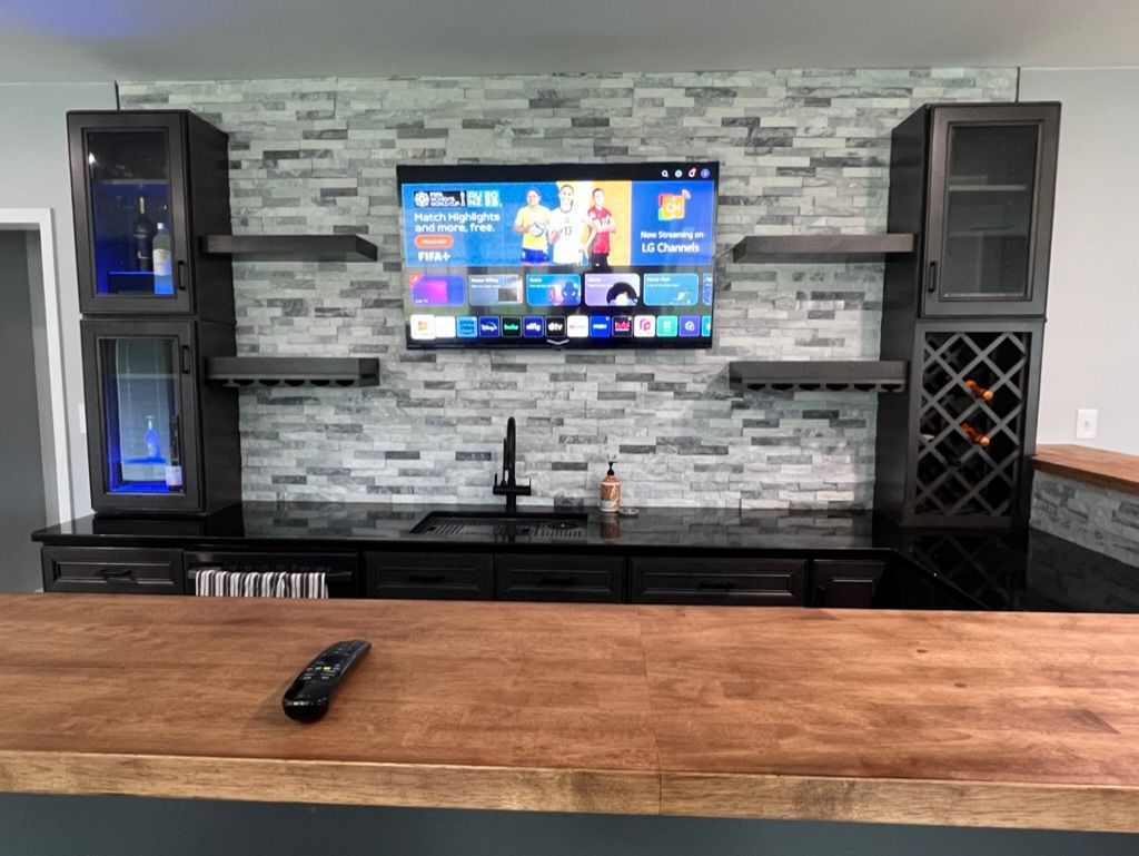 A bar with a television on the wall and a remote control on the counter.