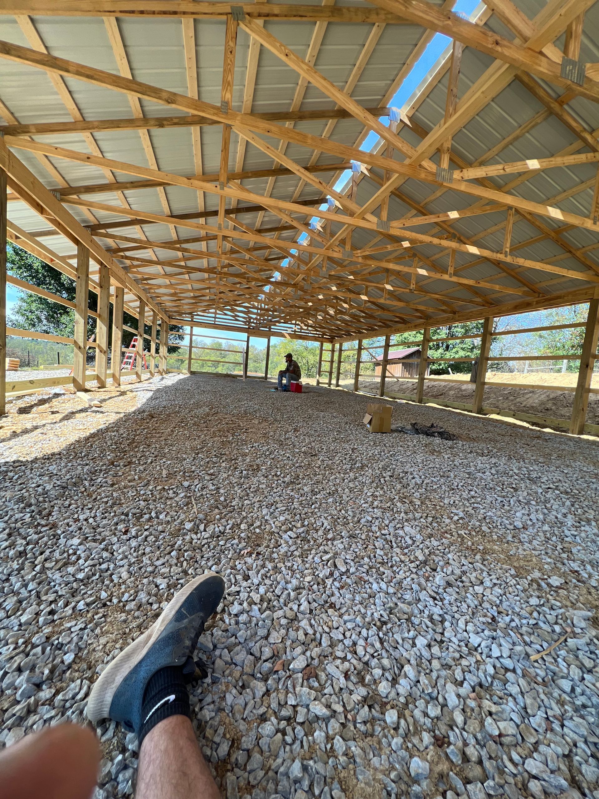 A person is laying on a pile of gravel under a wooden structure.