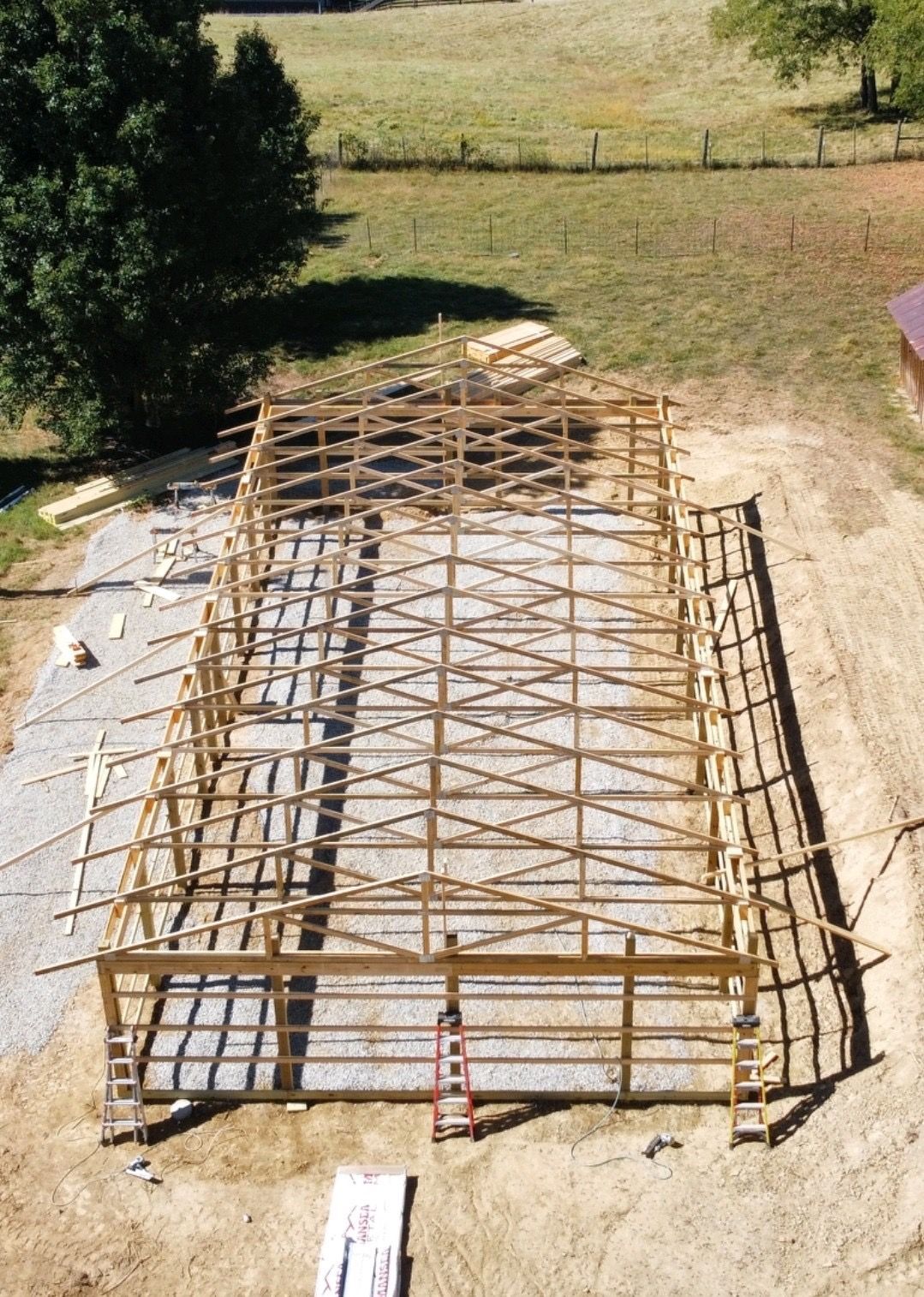 A large wooden structure is being built in a field.