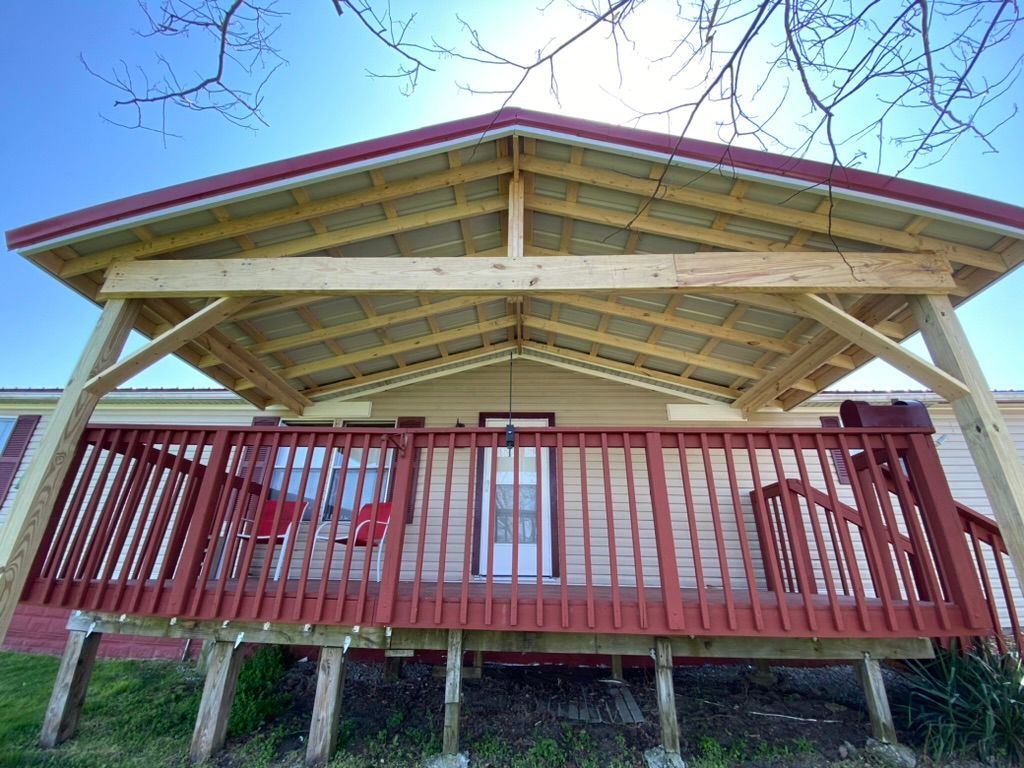 A mobile home with a red deck and a covered porch.