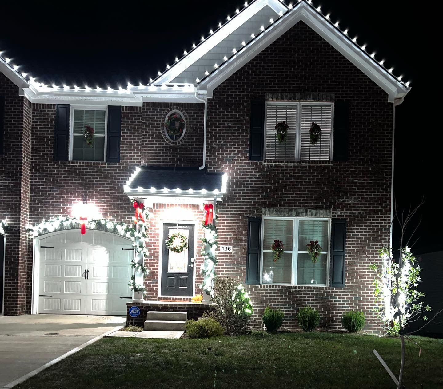 A brick house is decorated with christmas lights at night.