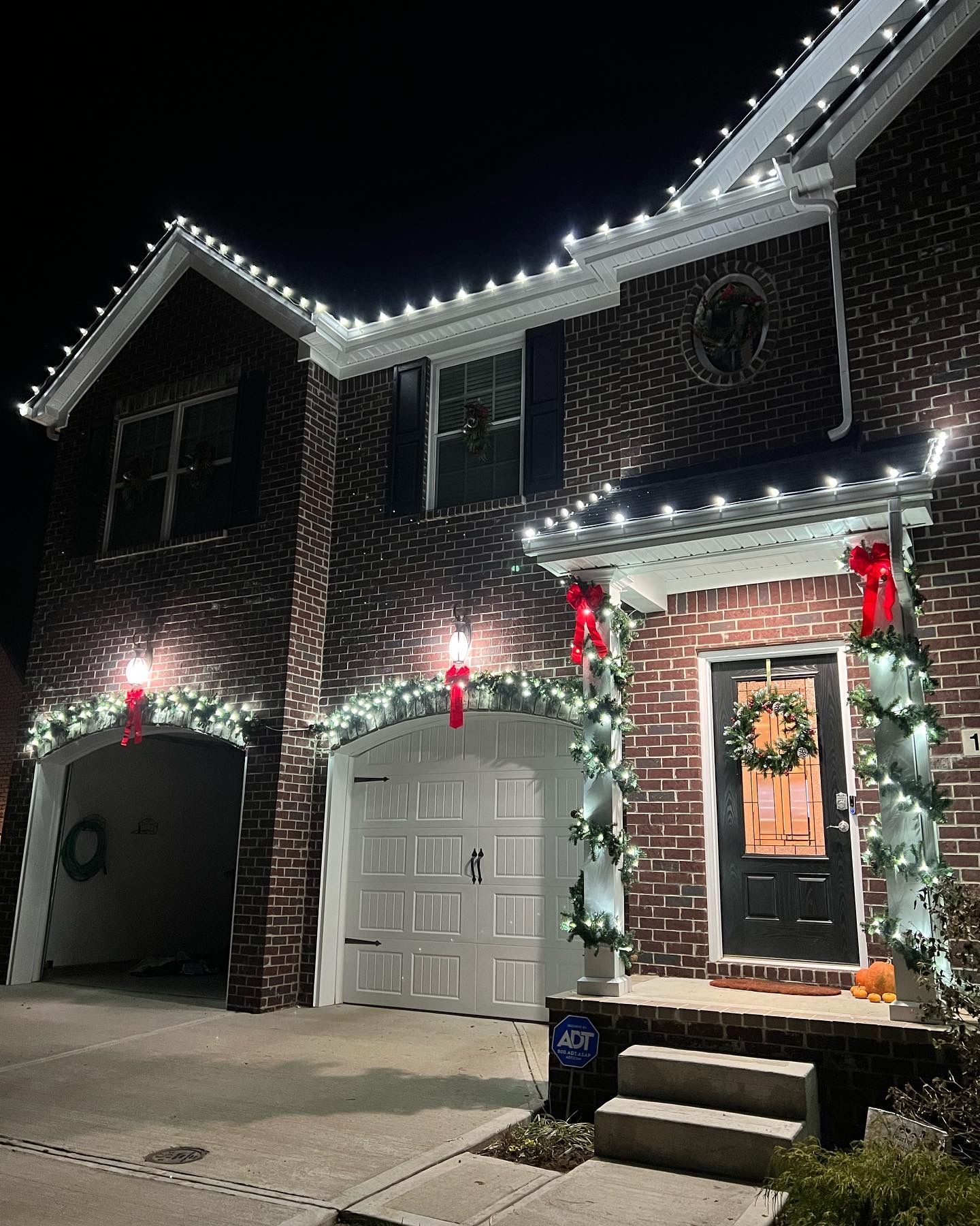 A brick house is decorated for christmas with christmas lights and a garland.