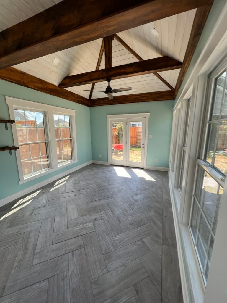 A large room with a lot of windows and a ceiling fan.