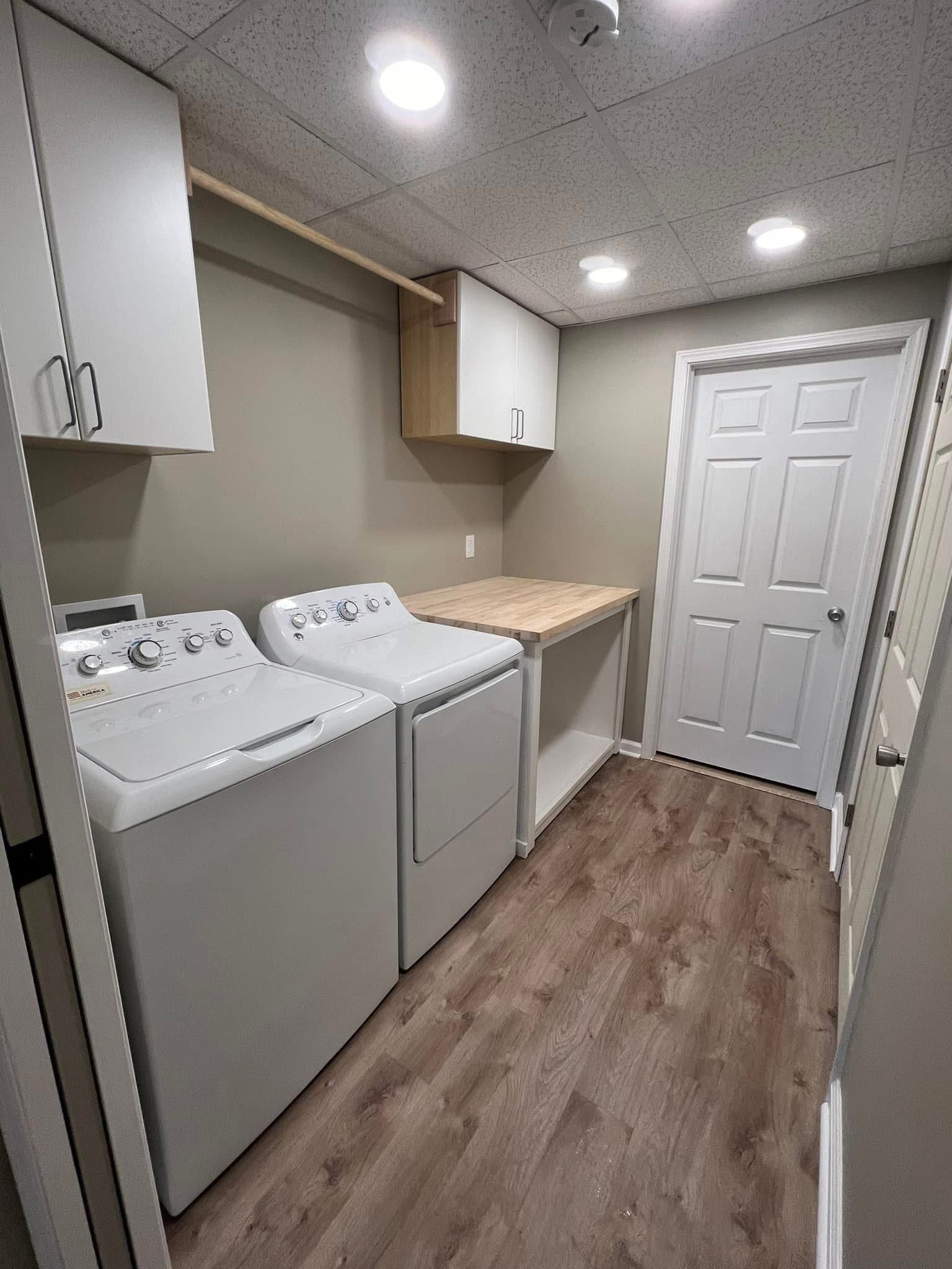 A laundry room with a washer and dryer and a wooden floor.