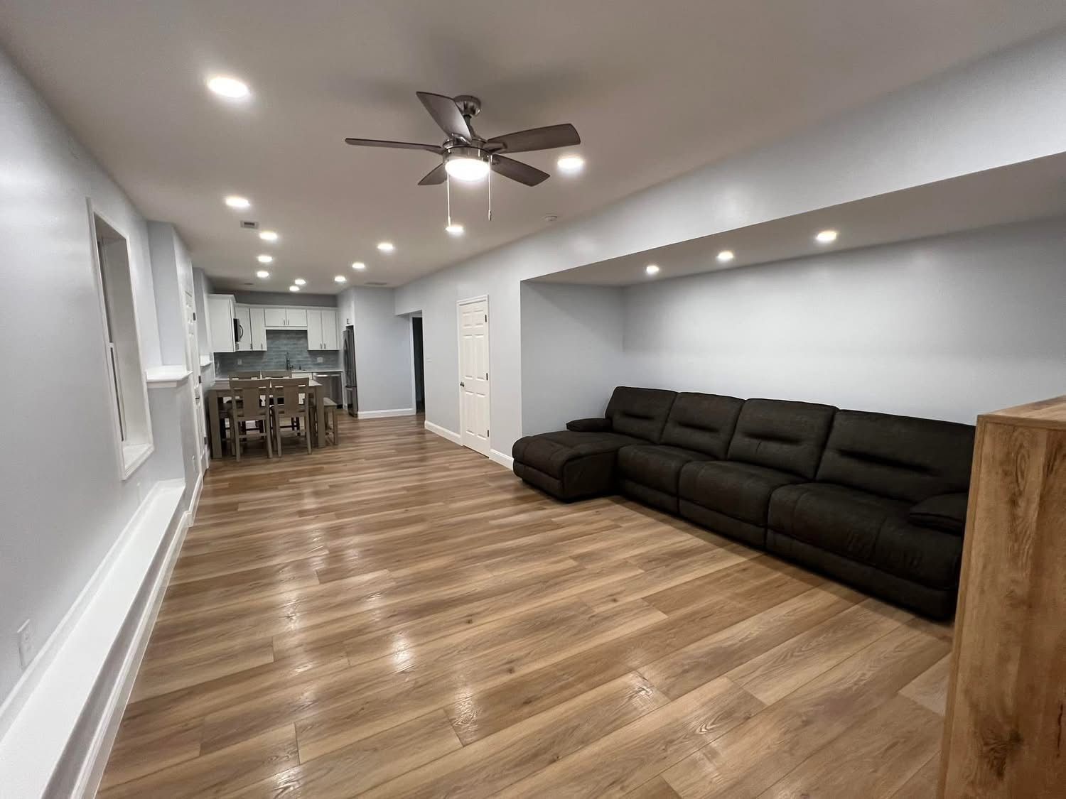 A living room with a black couch and a ceiling fan.