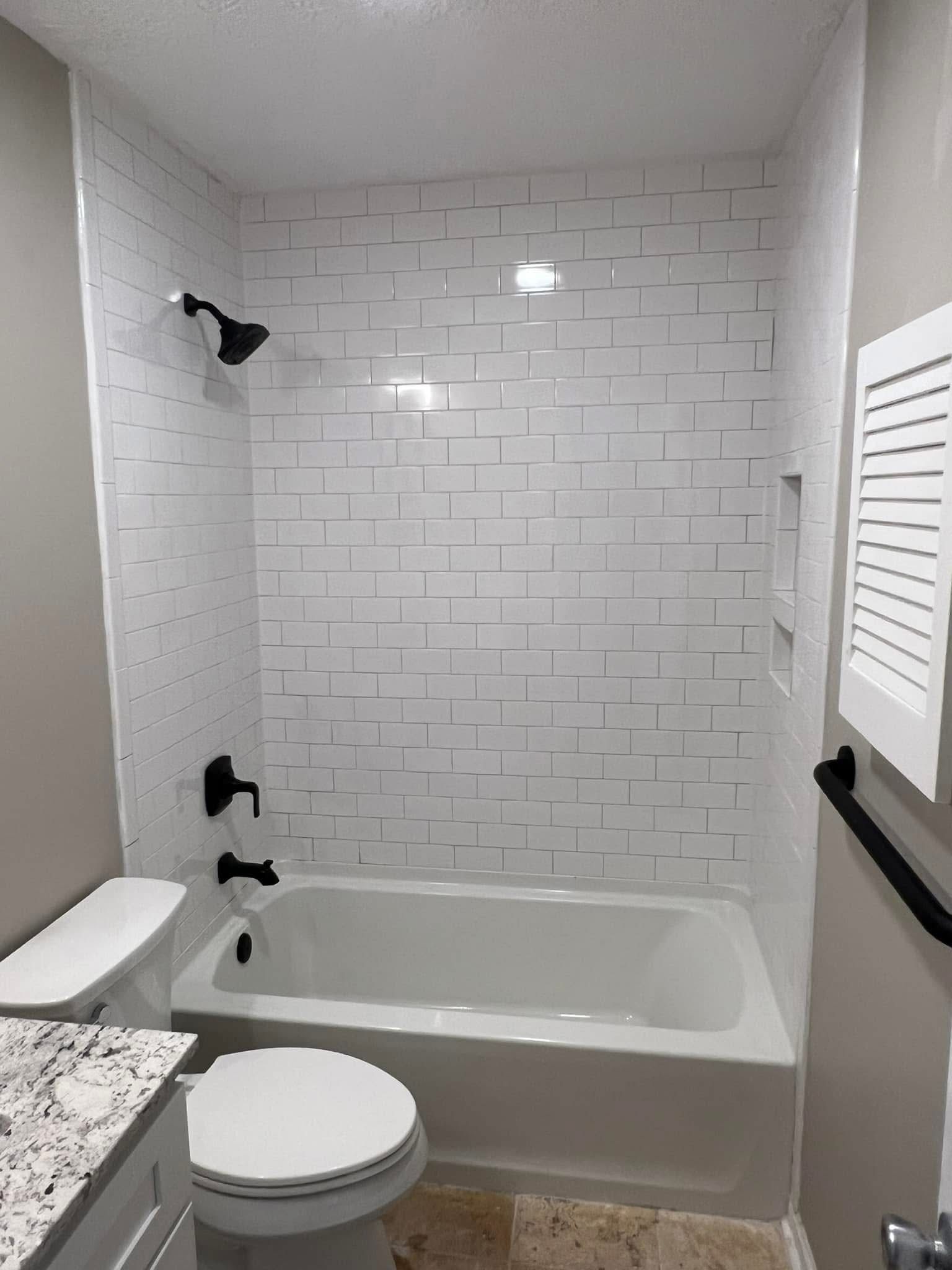 A bathroom with a toilet , bathtub and shower.
