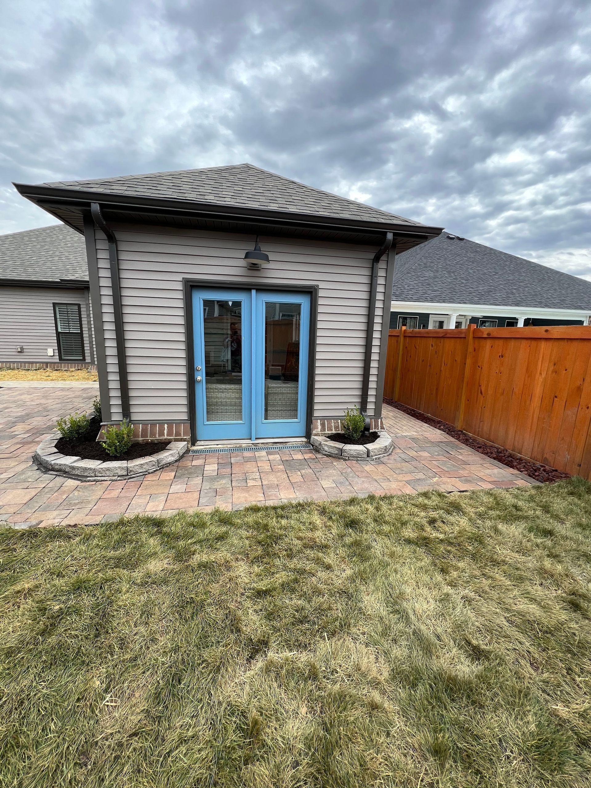 A small house with blue doors and a wooden fence in the backyard.