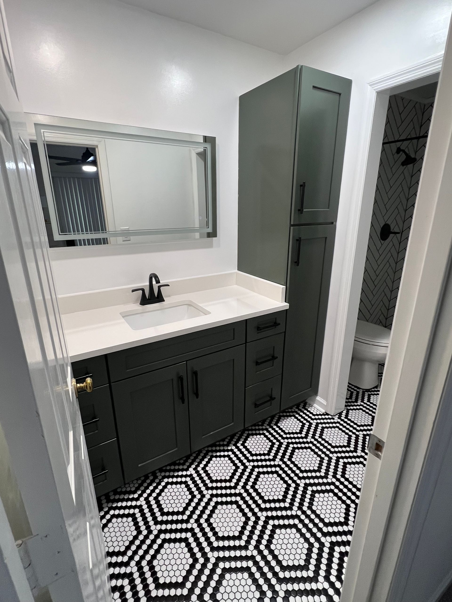 A bathroom with a sink , mirror , and black and white tile floor.