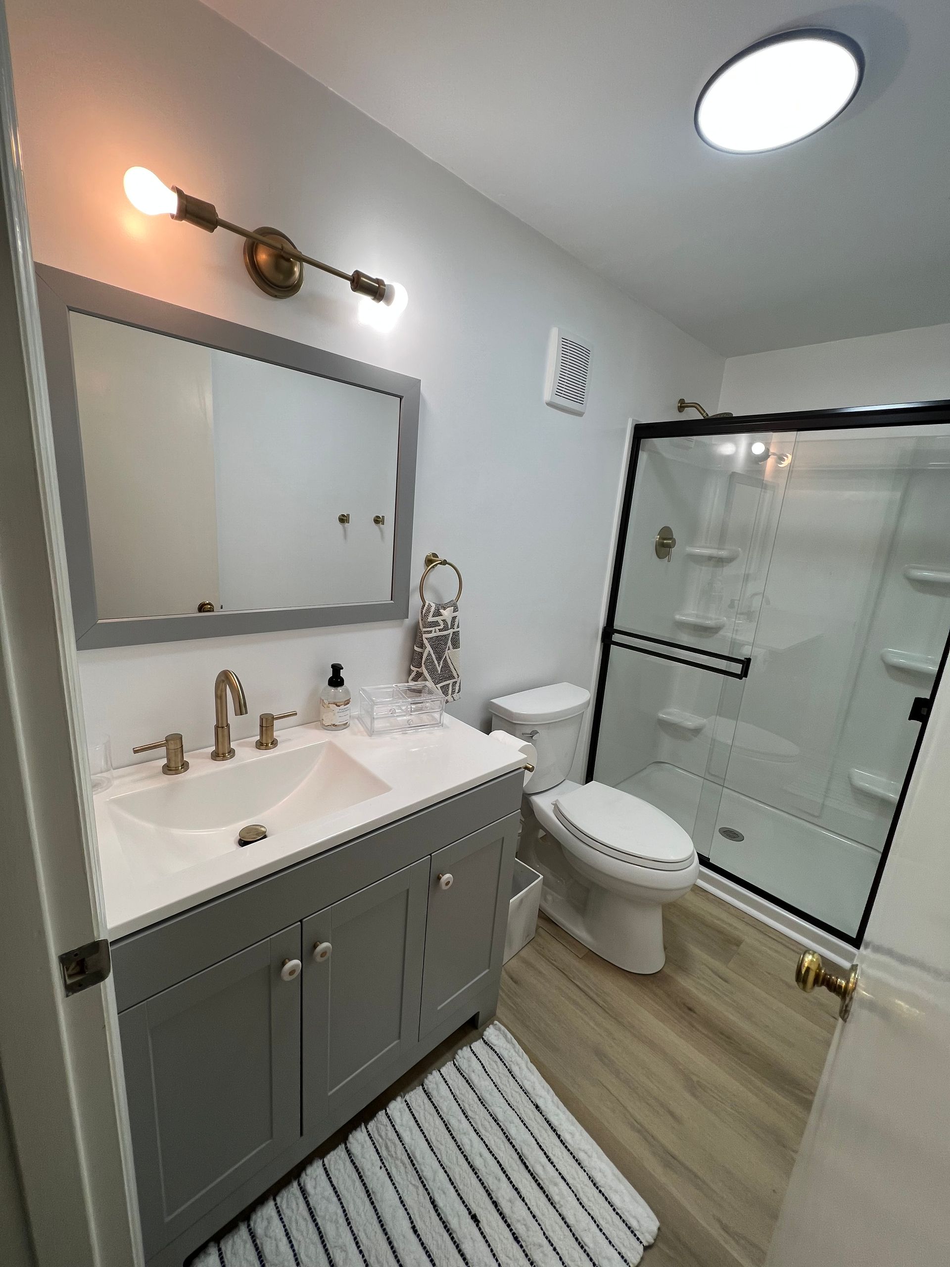 A bathroom with a sink , toilet , shower and mirror.