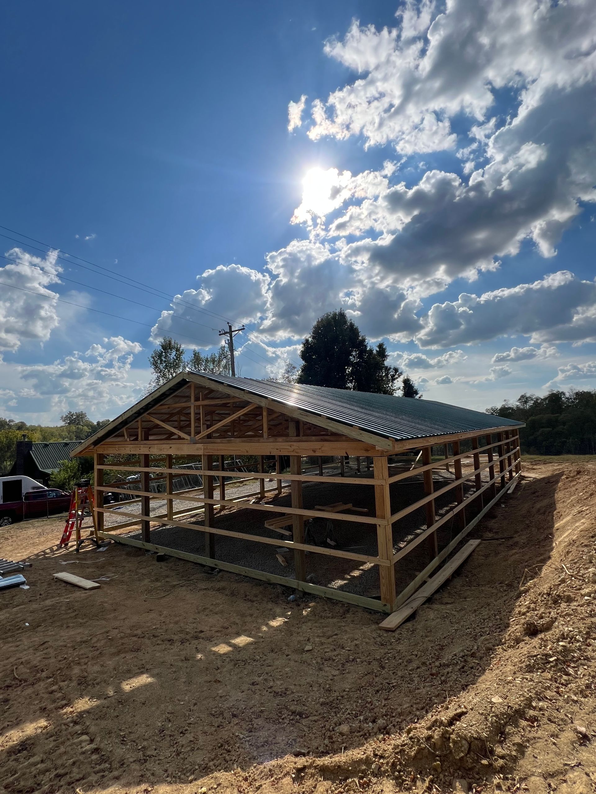 A large wooden building is being built in a dirt field.