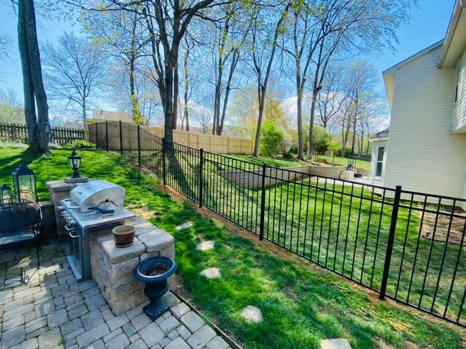 A patio with a grill and a fence in the backyard of a house.